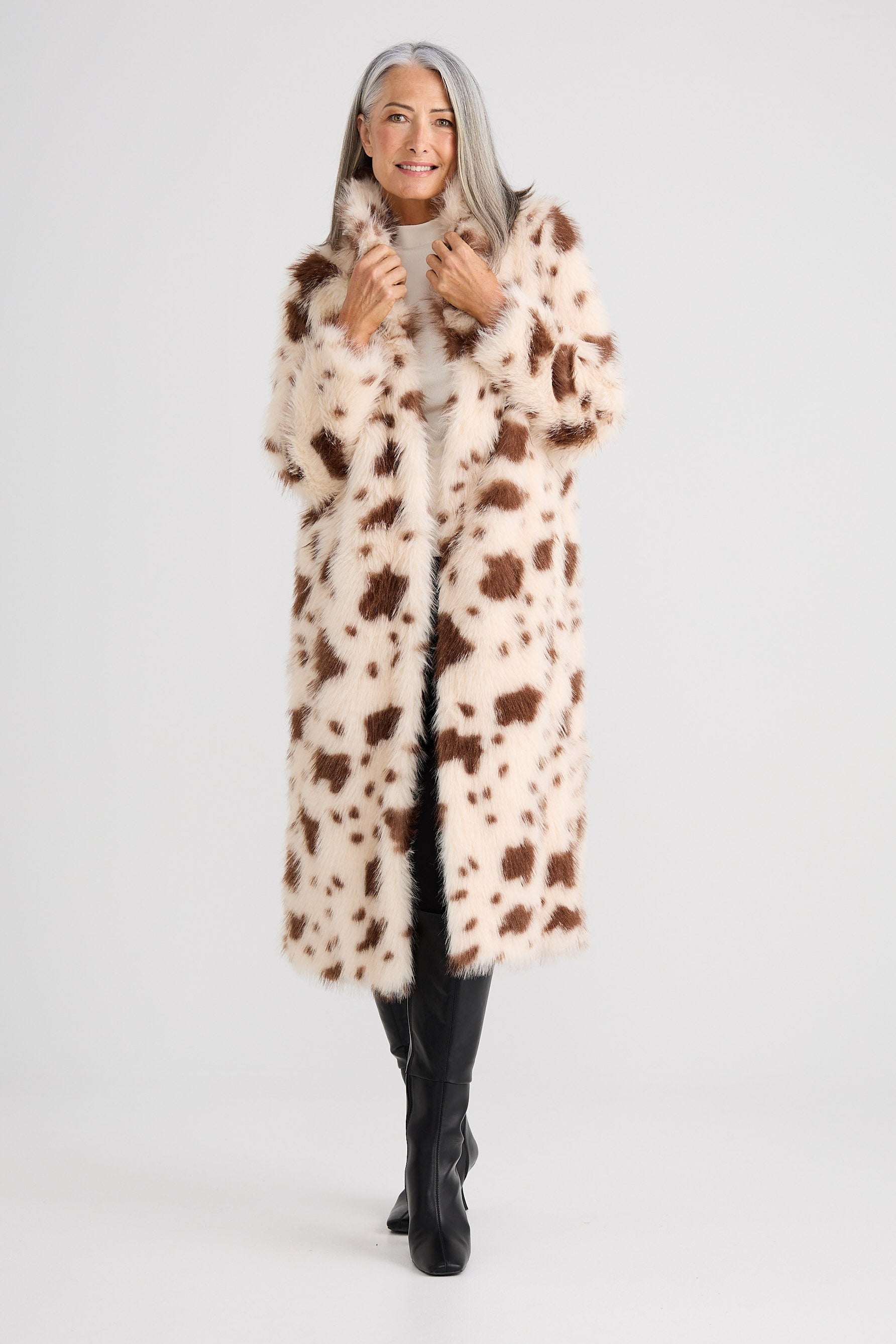 Person wearing a cow print coat on a white background