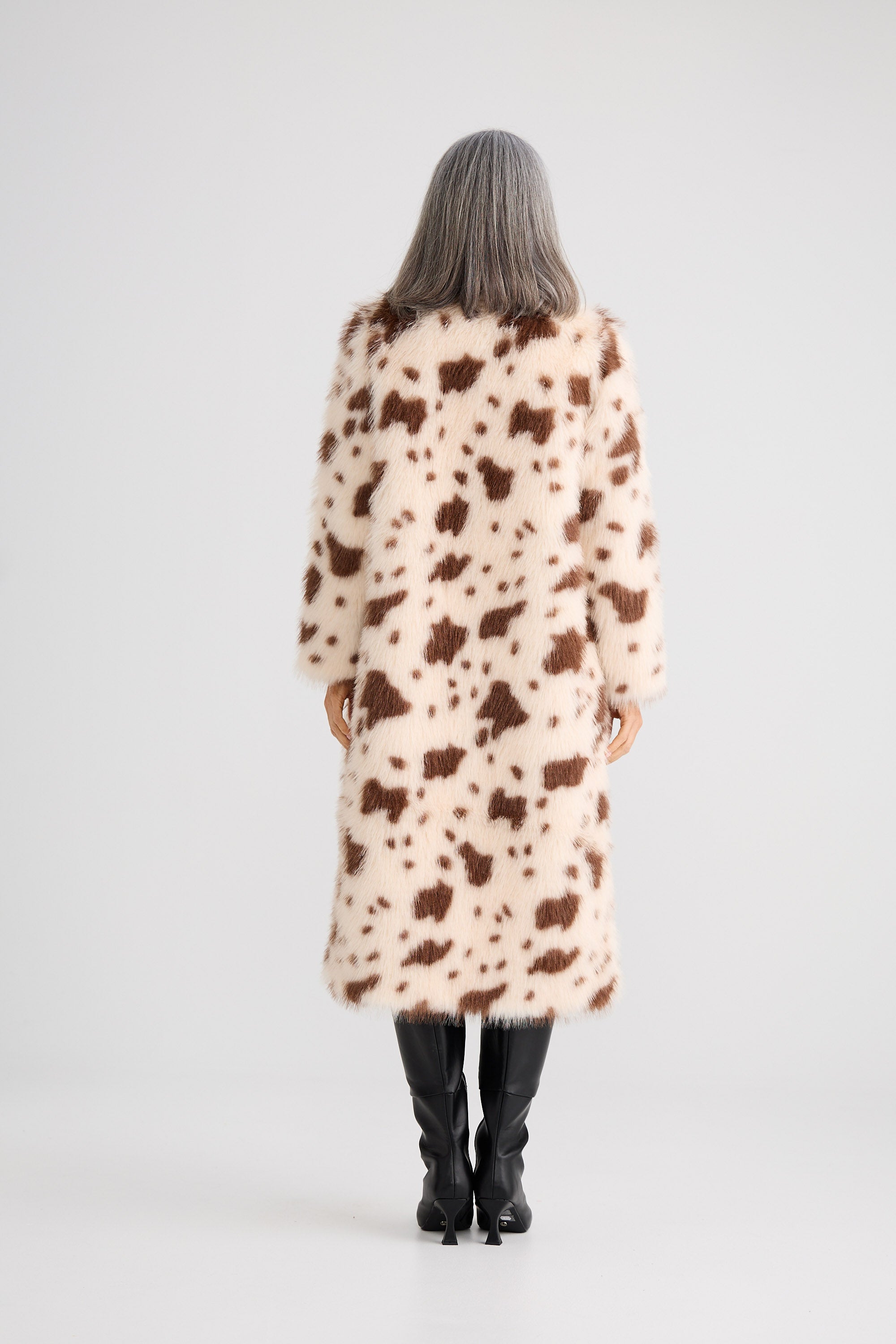 Person wearing a long, patterned coat on a white background