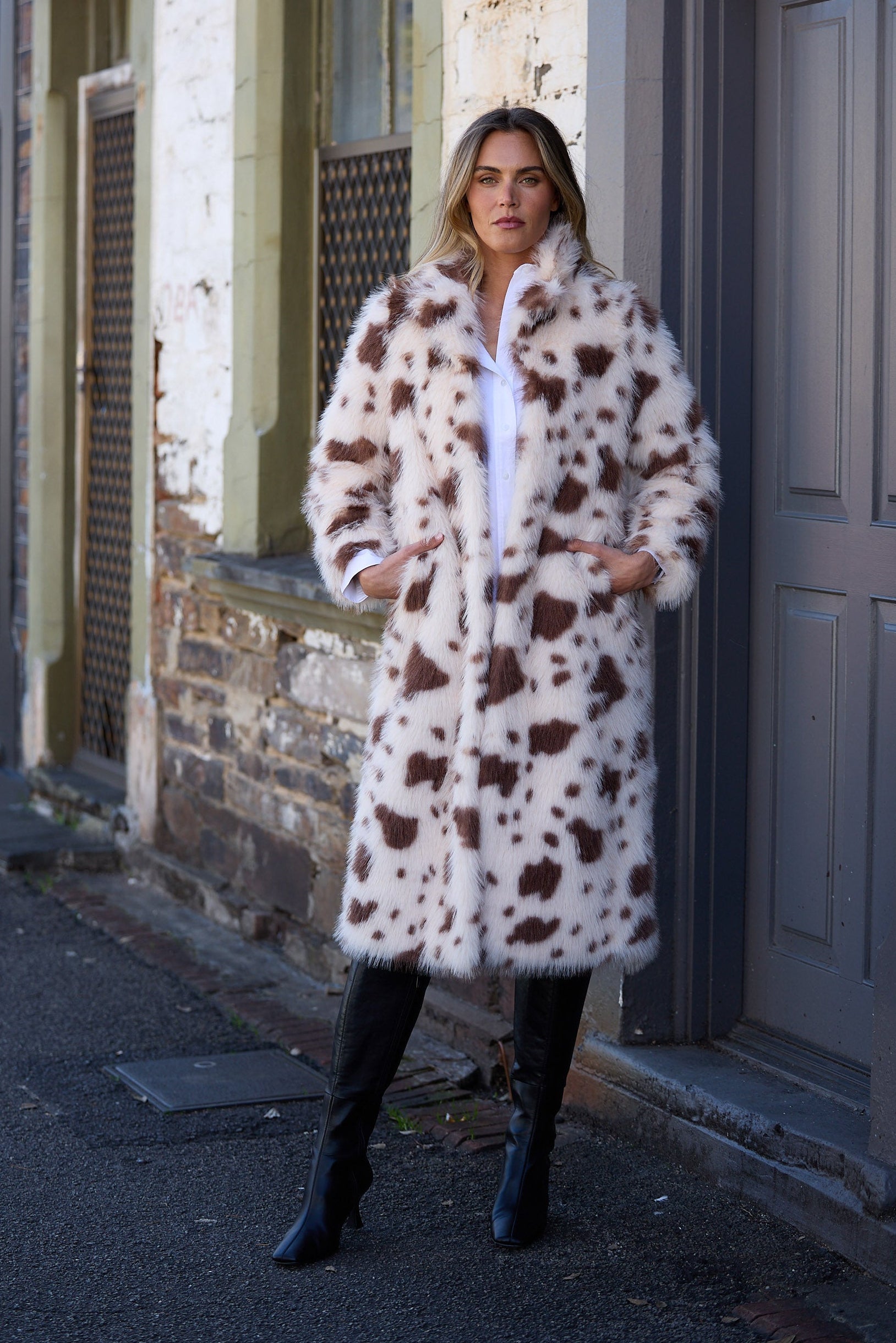 Woman wearing a patterned coat standing on a street.