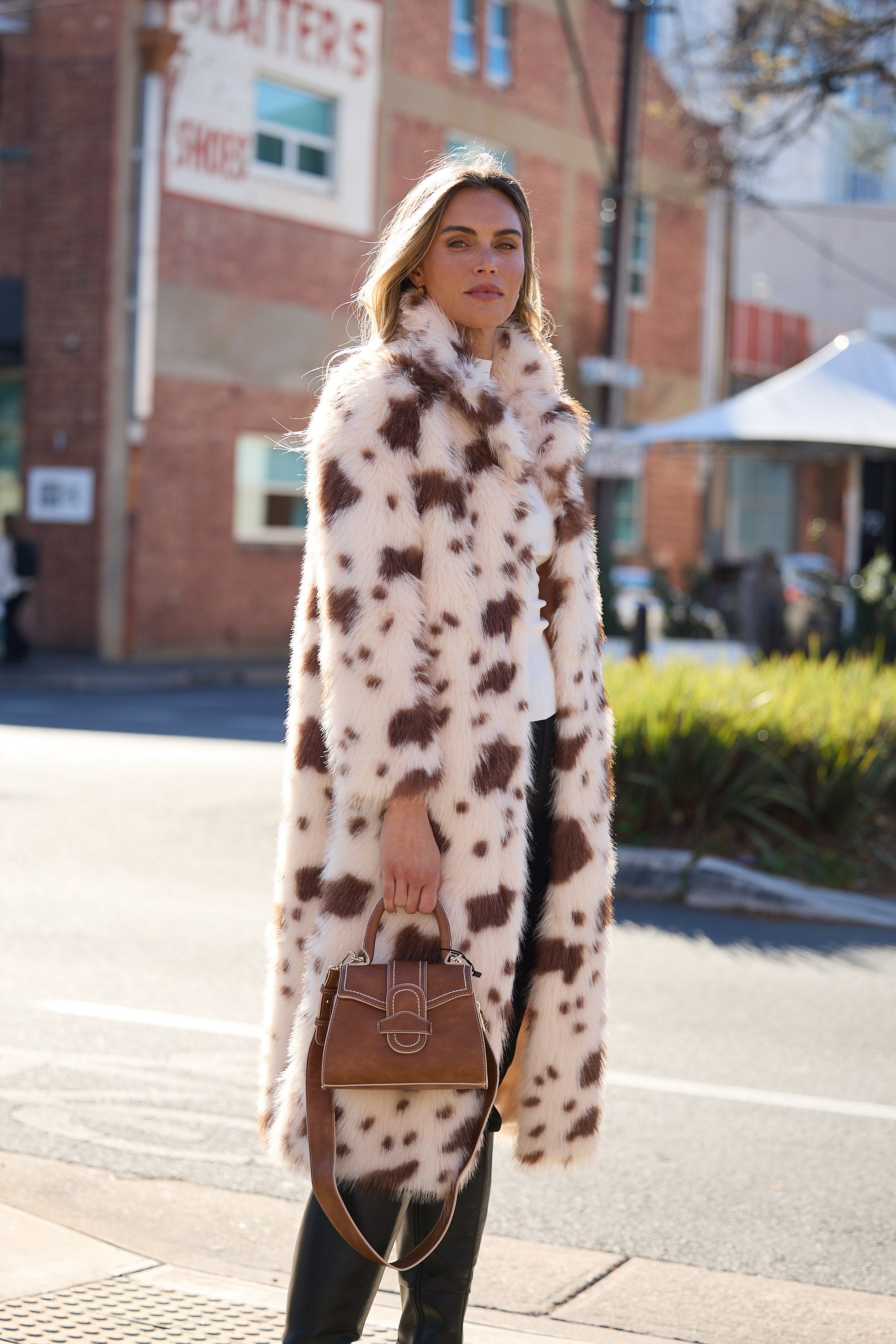 Woman wearing a long, patterned coat on a city street.