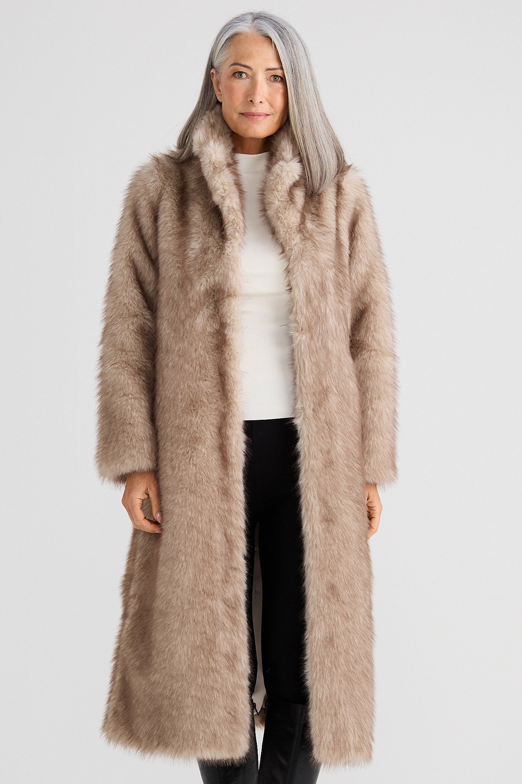 Woman wearing a long beige fur coat on a white background
