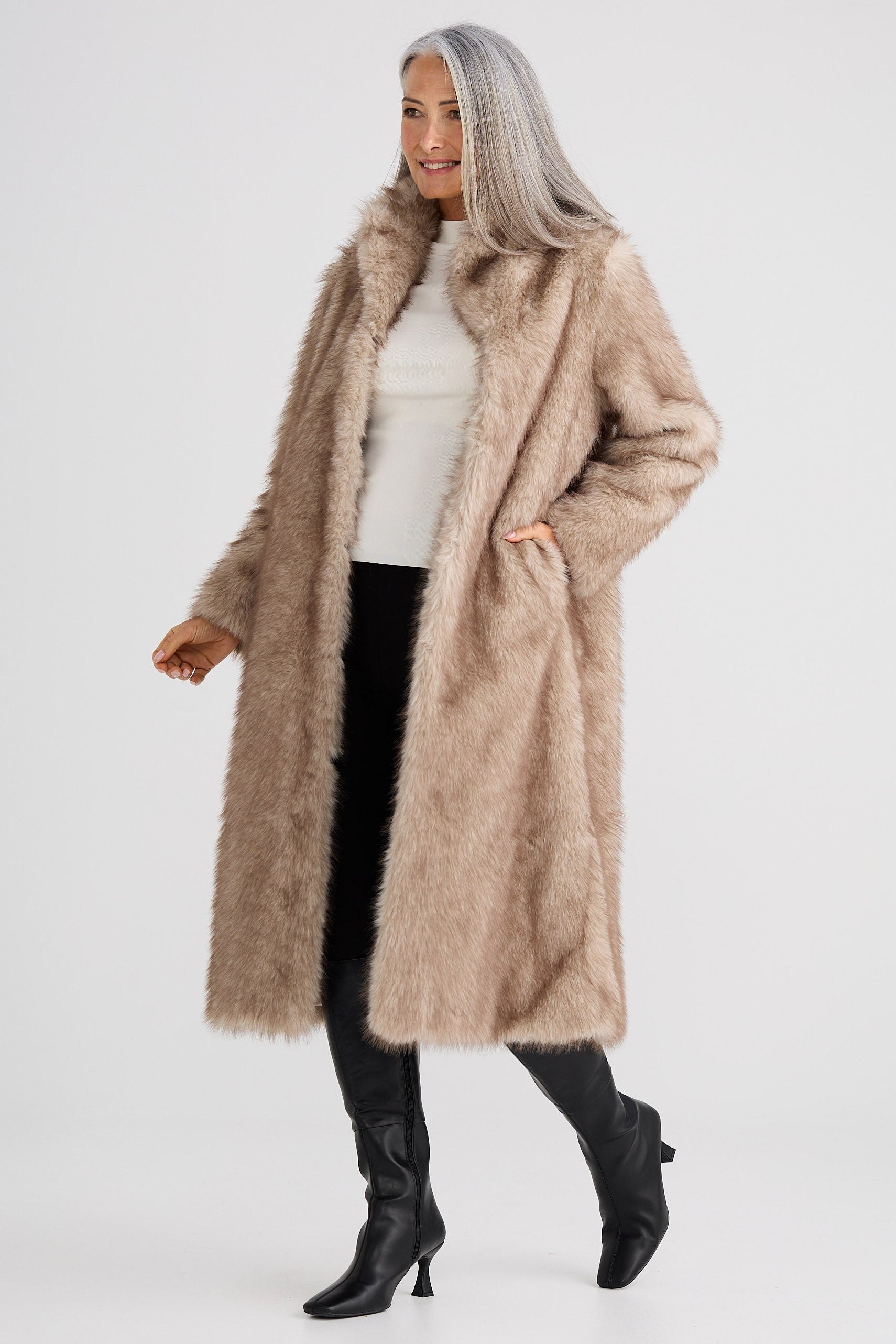 Woman wearing a long beige coat on a white background