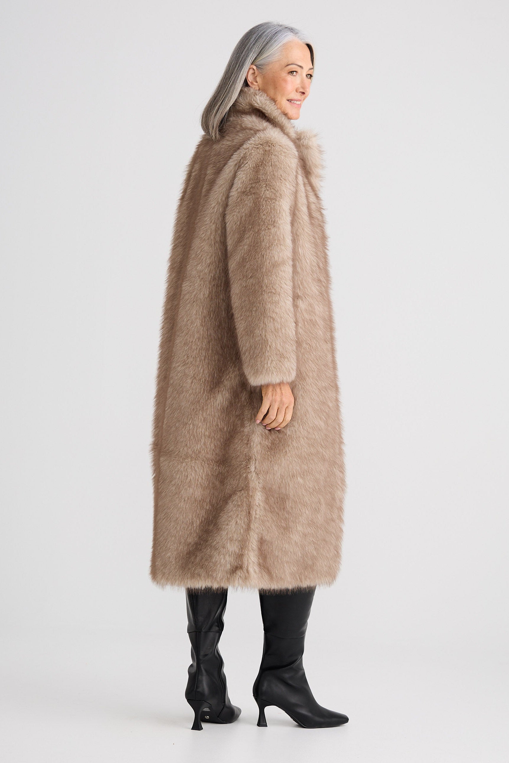 Woman wearing a long beige coat on a white background