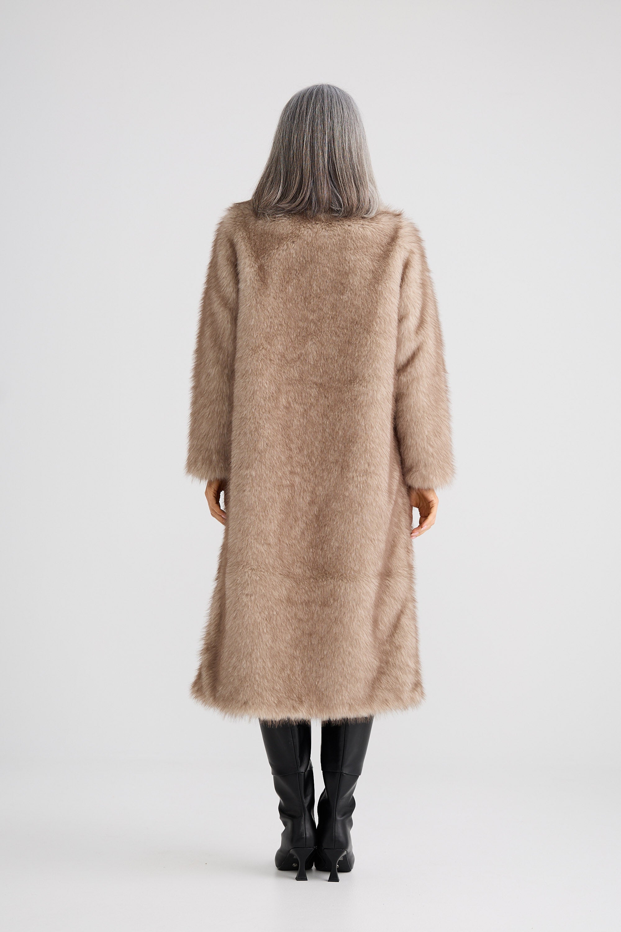 Person wearing a long beige coat on a white background