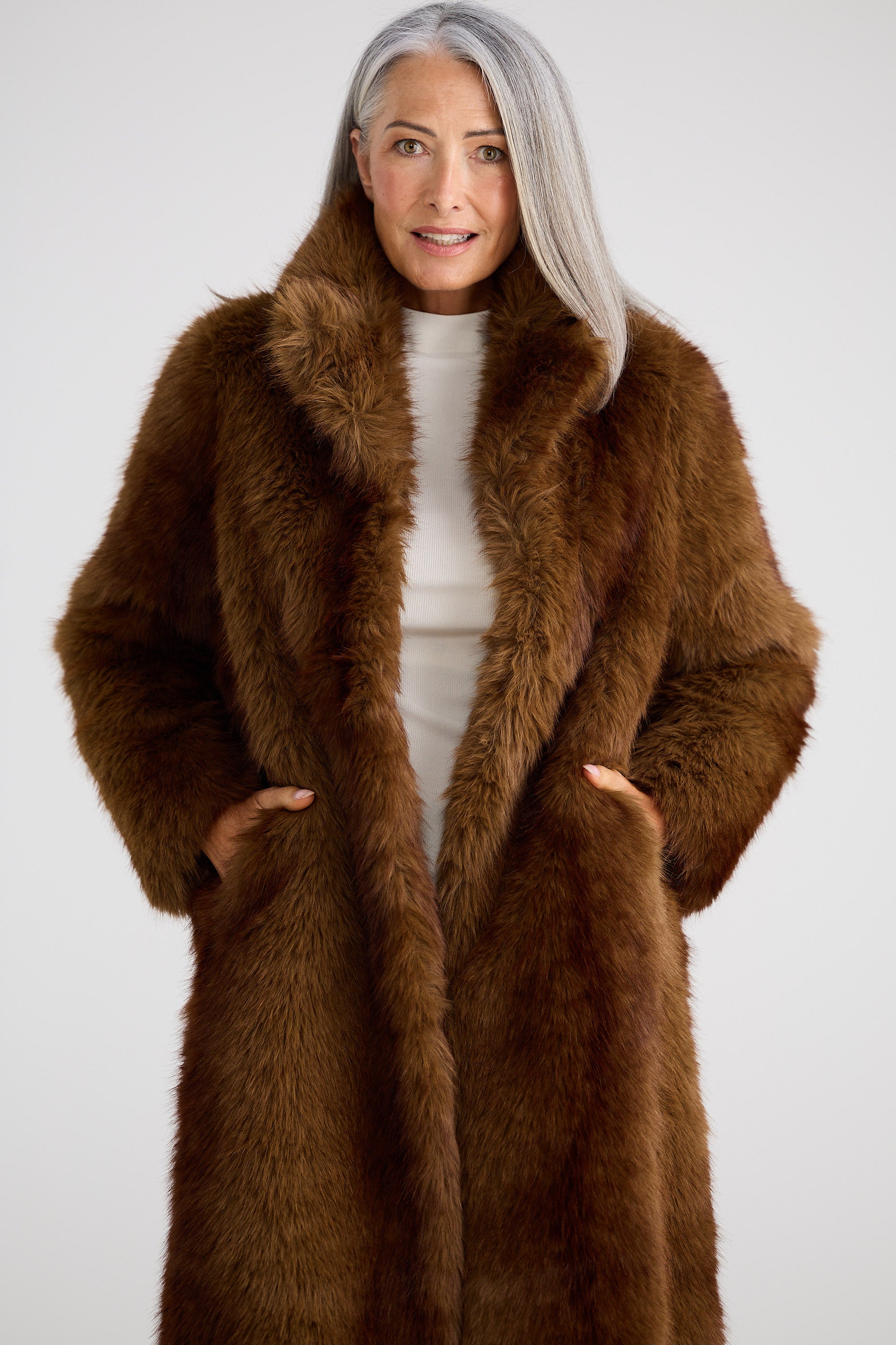 Person wearing a brown fur coat against a white background