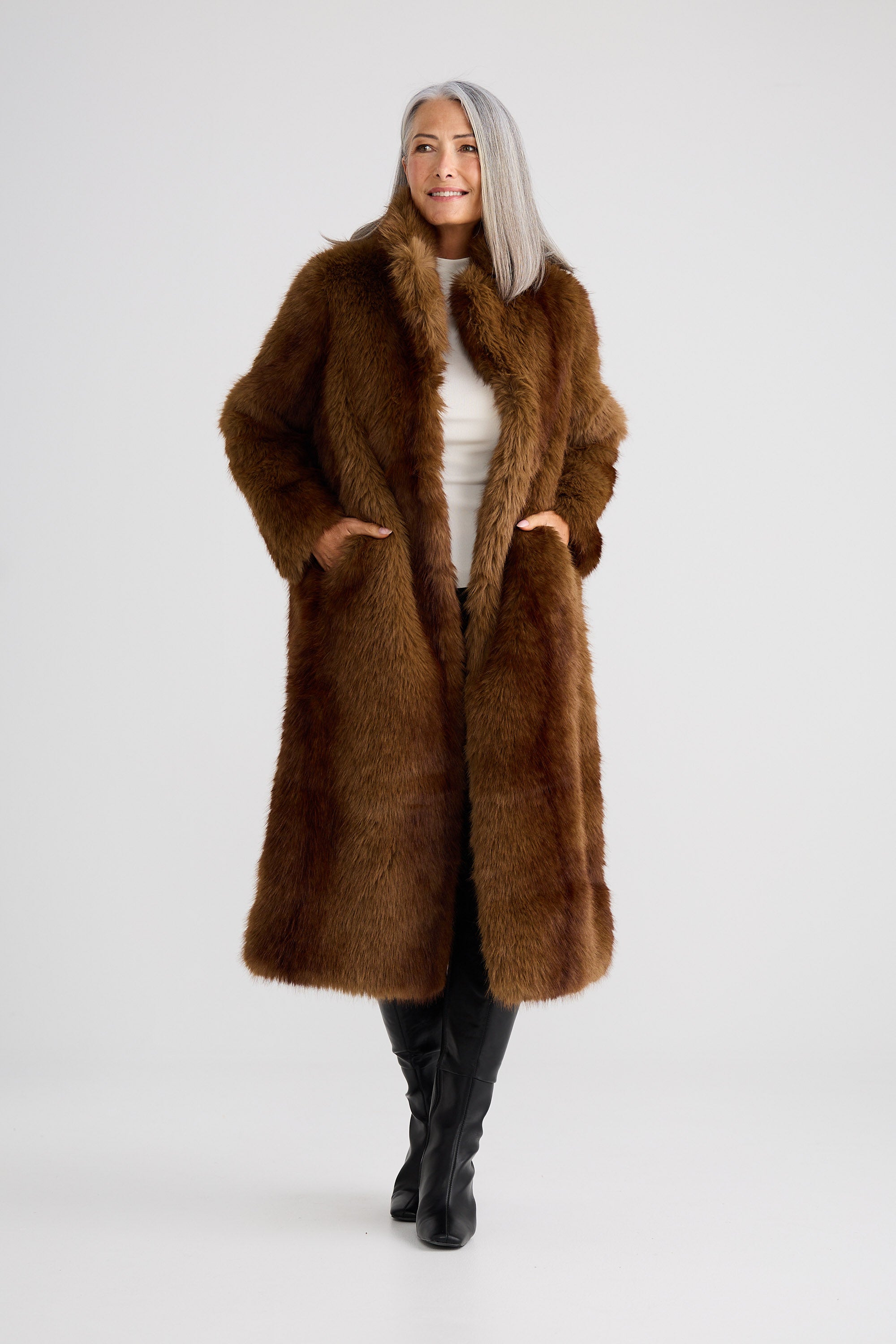 Woman wearing a long brown fur coat on a white background