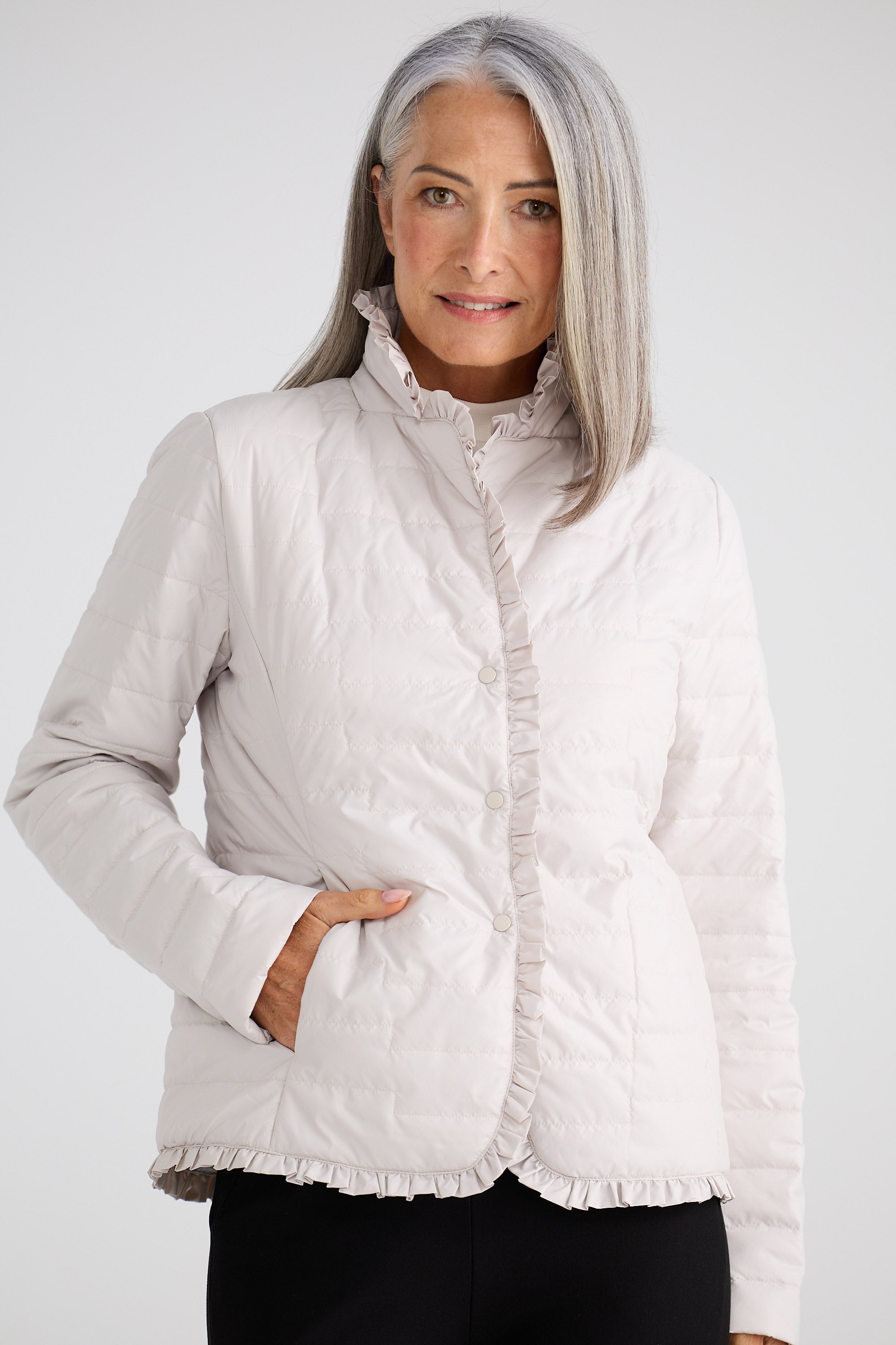 Woman wearing a white quilted jacket on a plain background