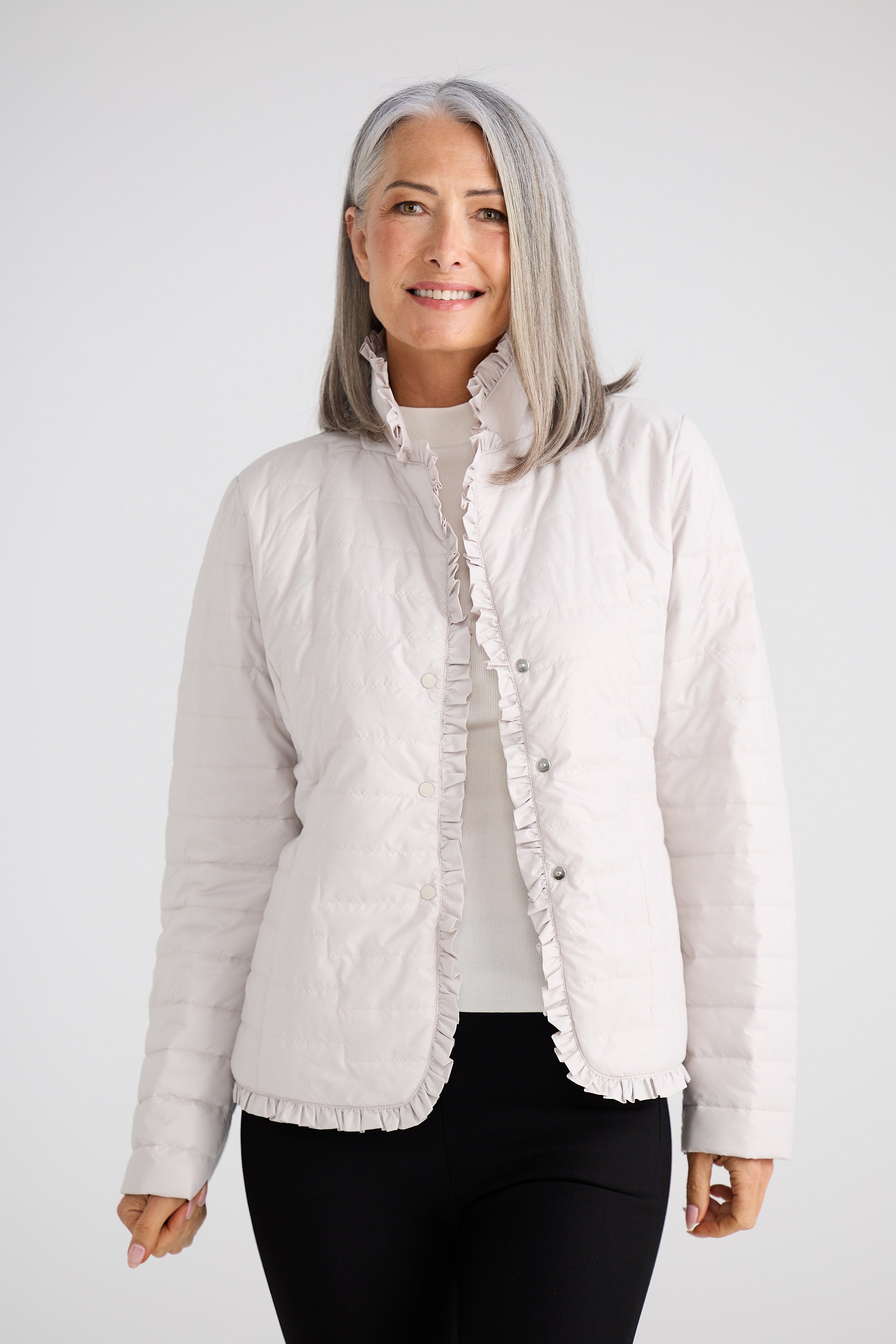 Woman wearing a light gray quilted jacket on a white background