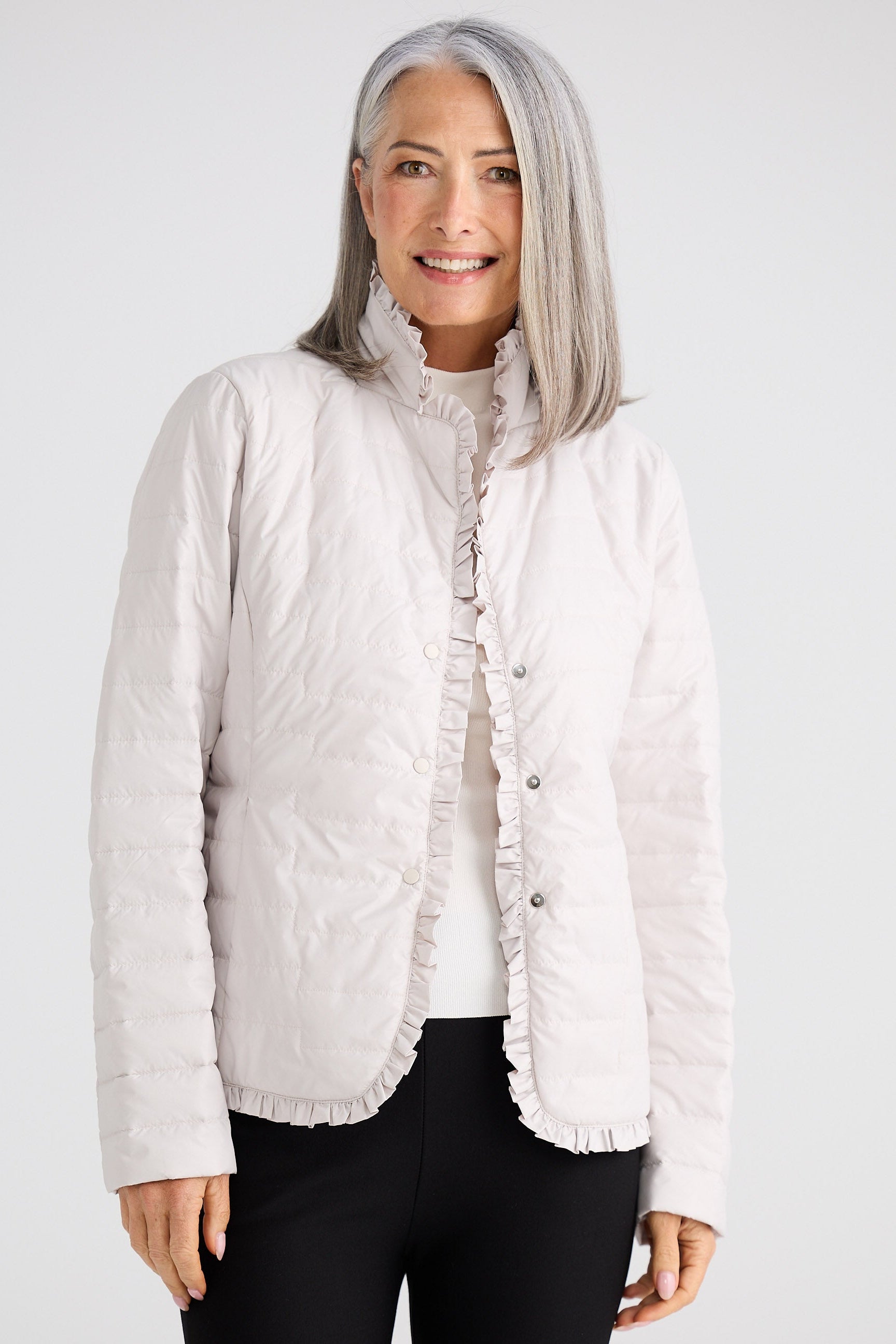 Woman wearing a light-colored quilted jacket on a white background