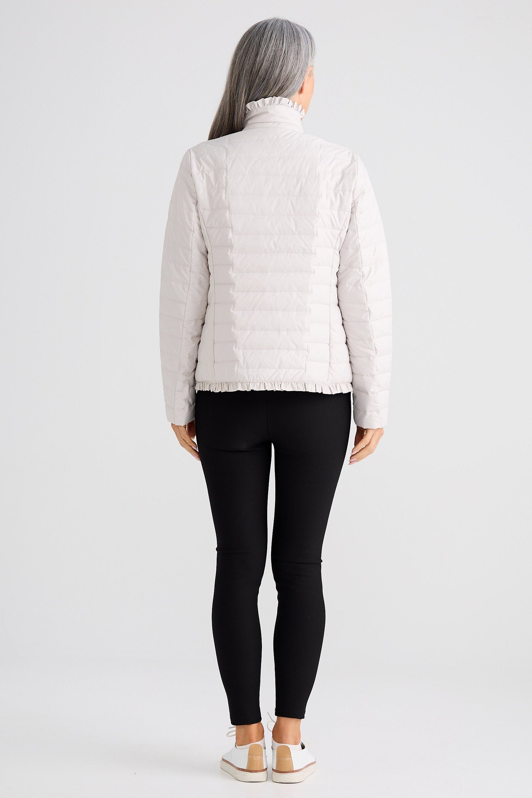 Person wearing a white puffer jacket and black leggings on a white background