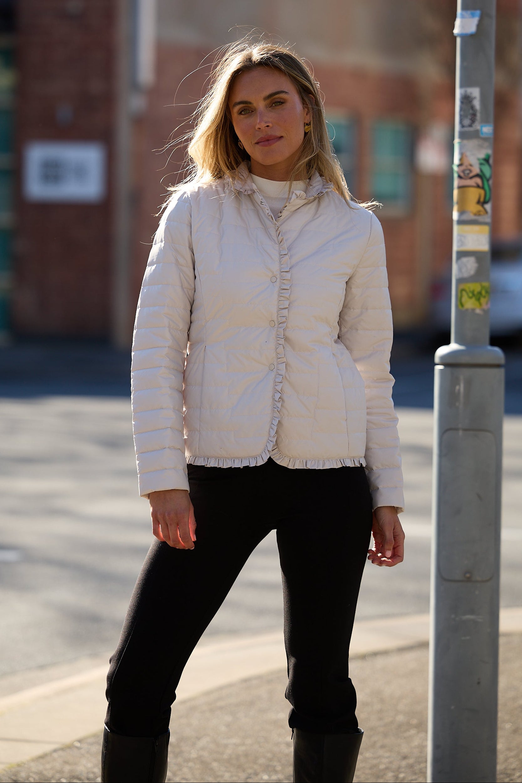 Woman wearing a white quilted jacket on a city street