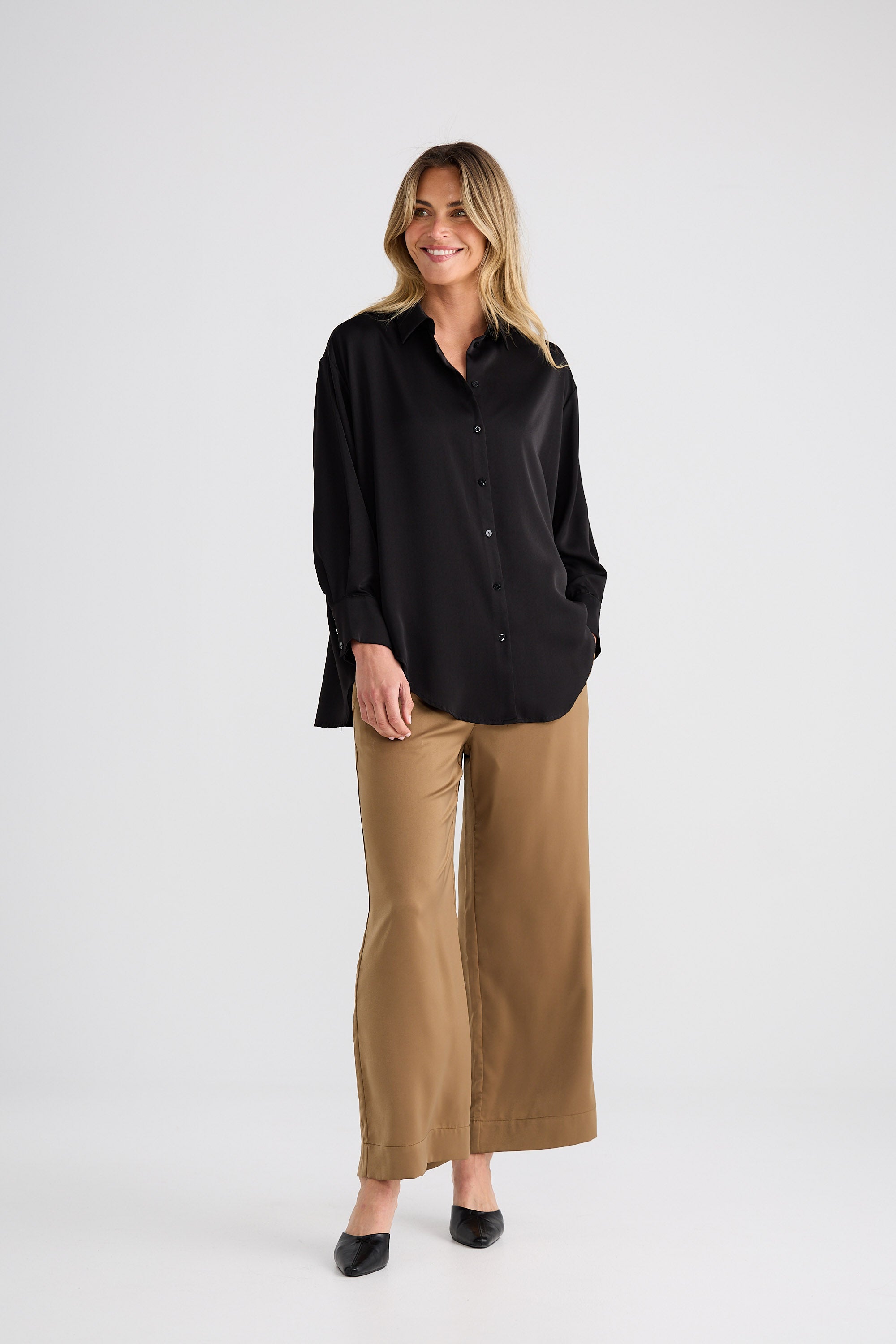 Woman wearing a black shirt and beige pants on a white background