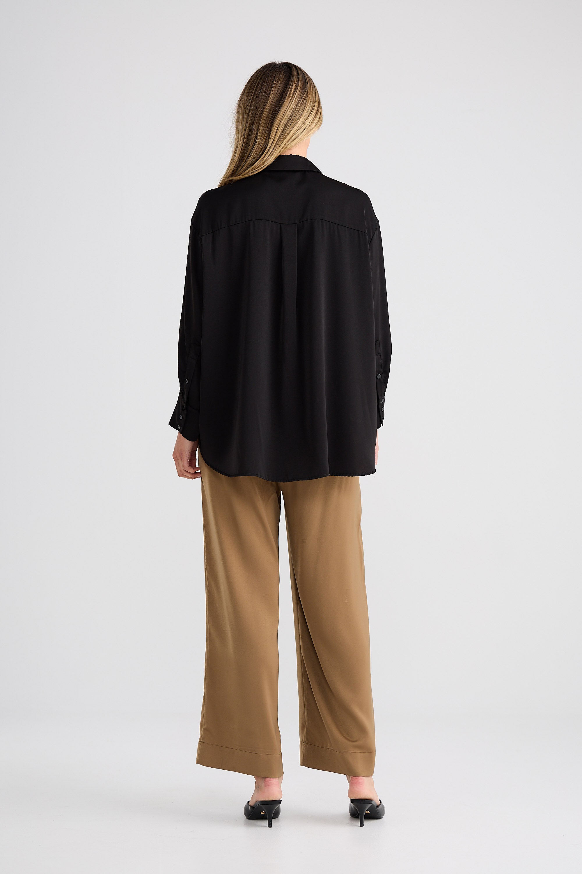 Person wearing a black shirt and beige pants on a white background