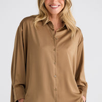 Woman wearing a beige button-up shirt against a white background