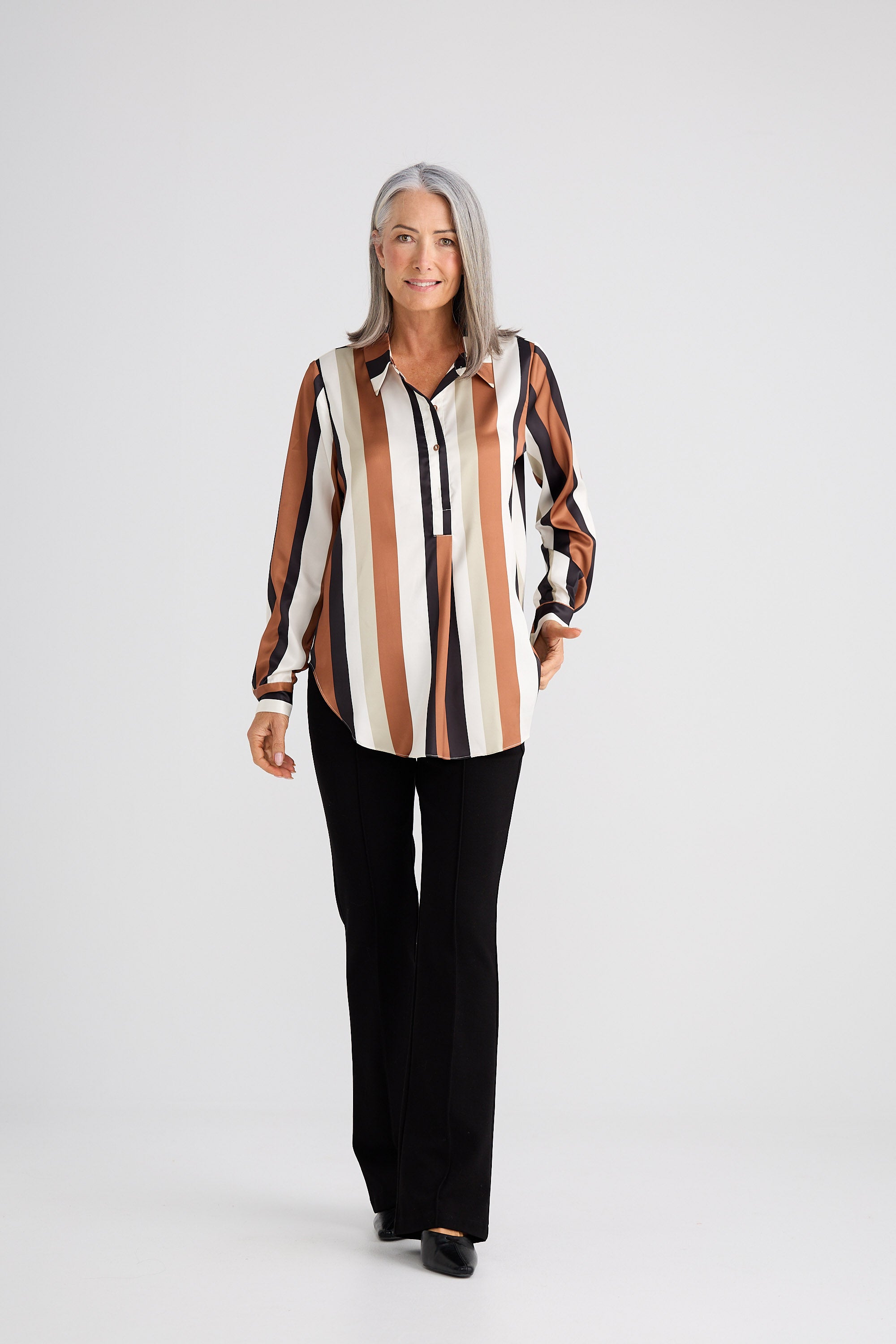 Woman wearing a striped shirt and black pants on a white background