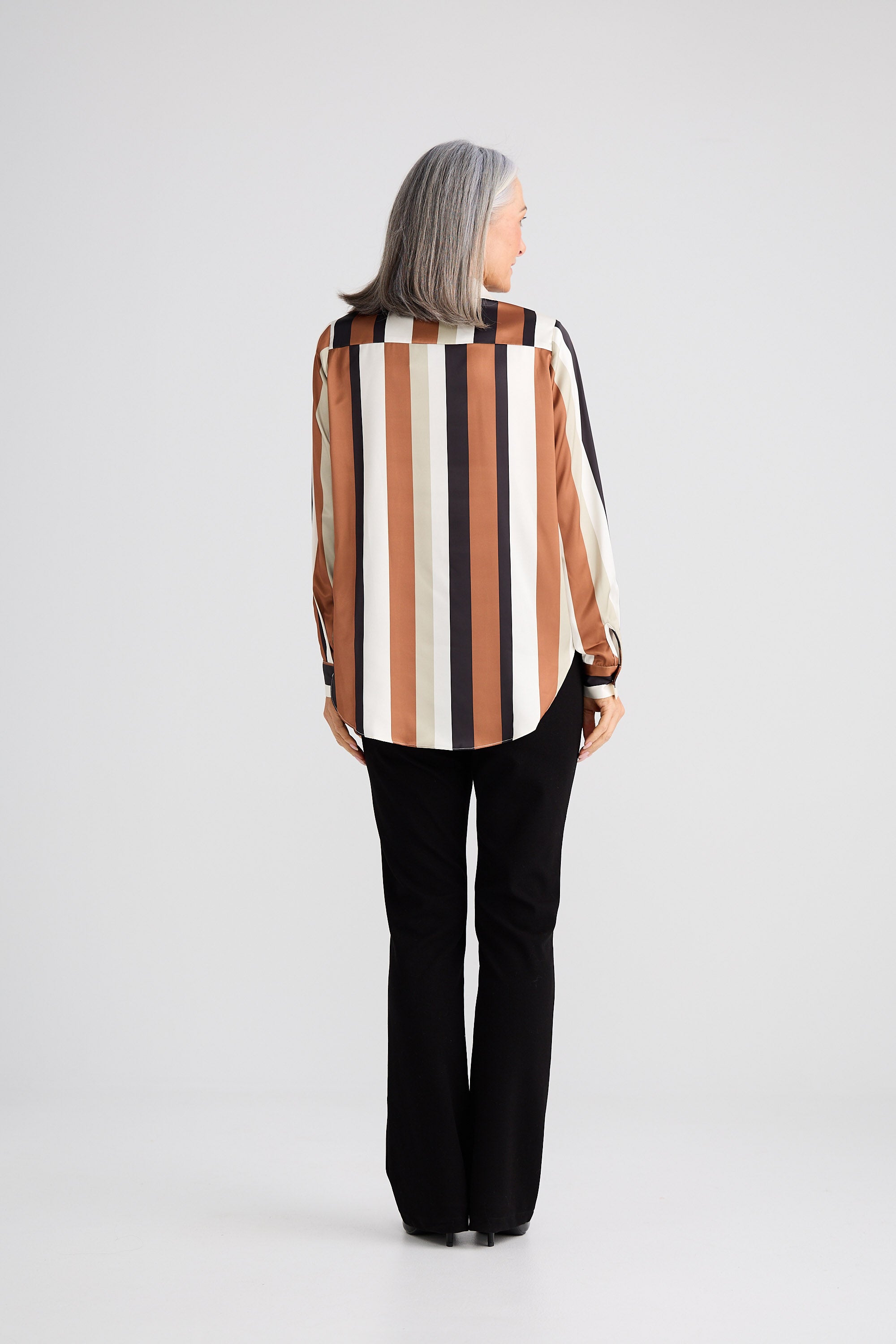 Person wearing a striped shirt and black pants on a white background