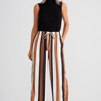Woman wearing a black sleeveless top and striped pants on a white background