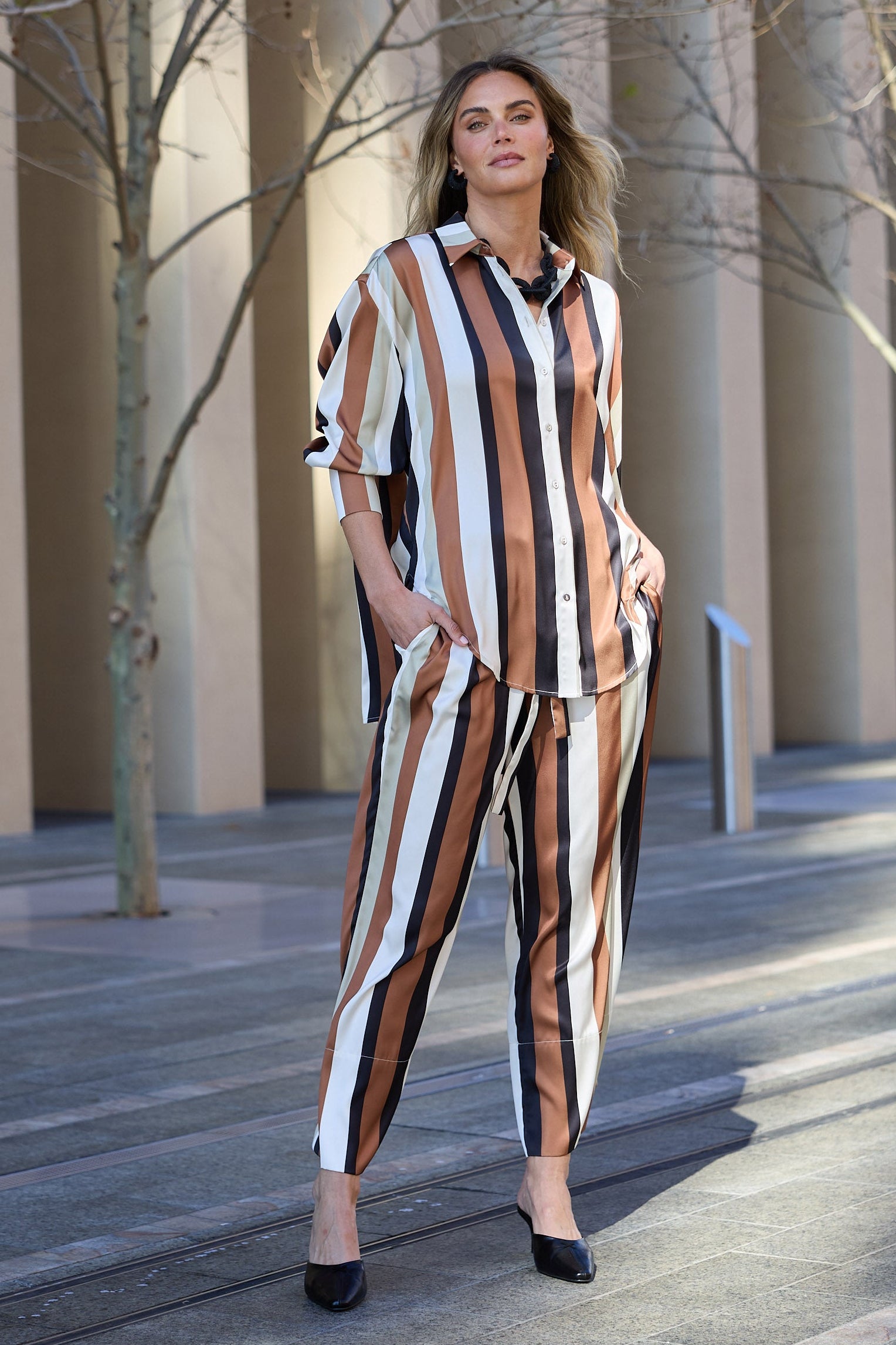 Woman in a striped outfit standing outdoors with architectural columns in the background