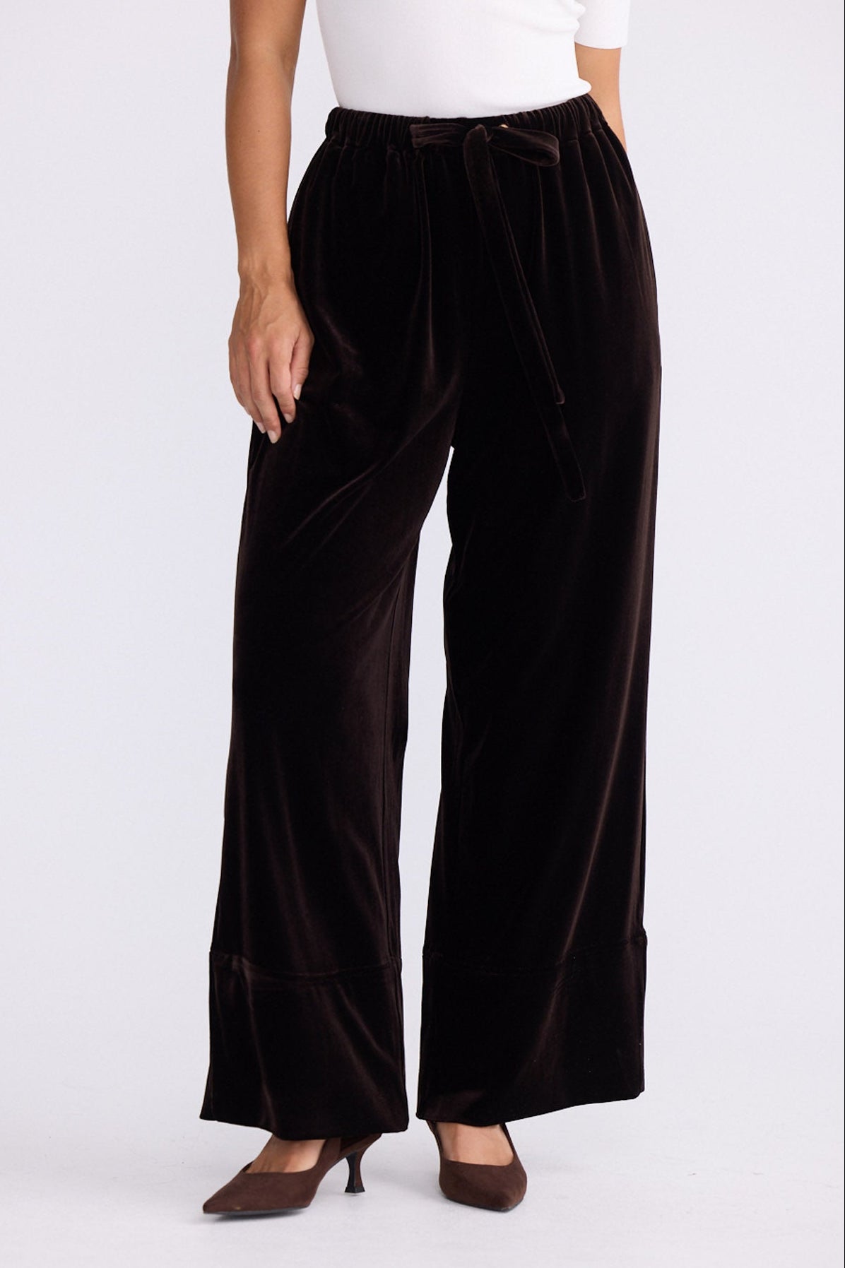 Model wearing Astrid Pant brown pants, relaxed wide-leg fit, alternate studio view on white background