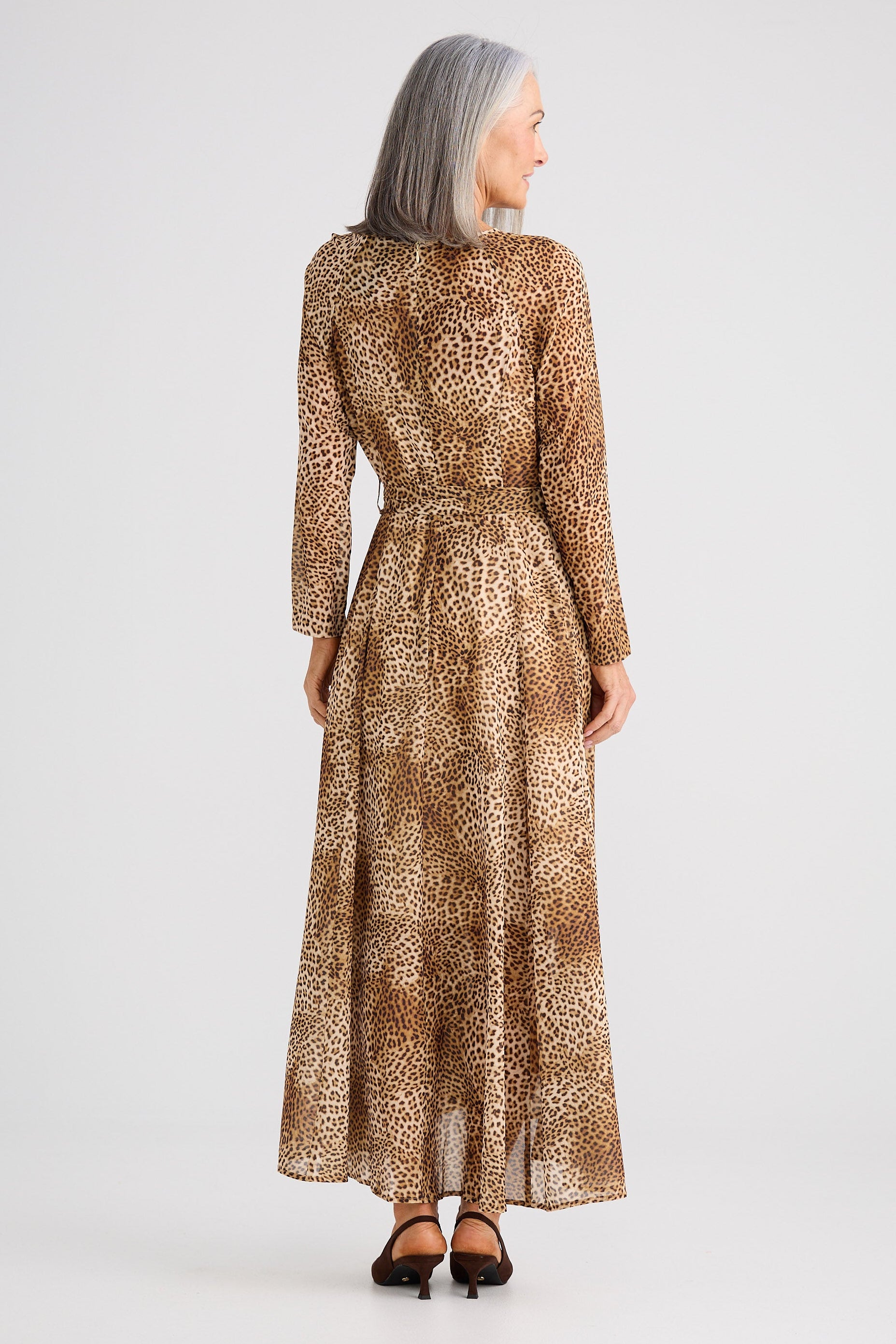 Woman wearing a long, patterned dress on a white background