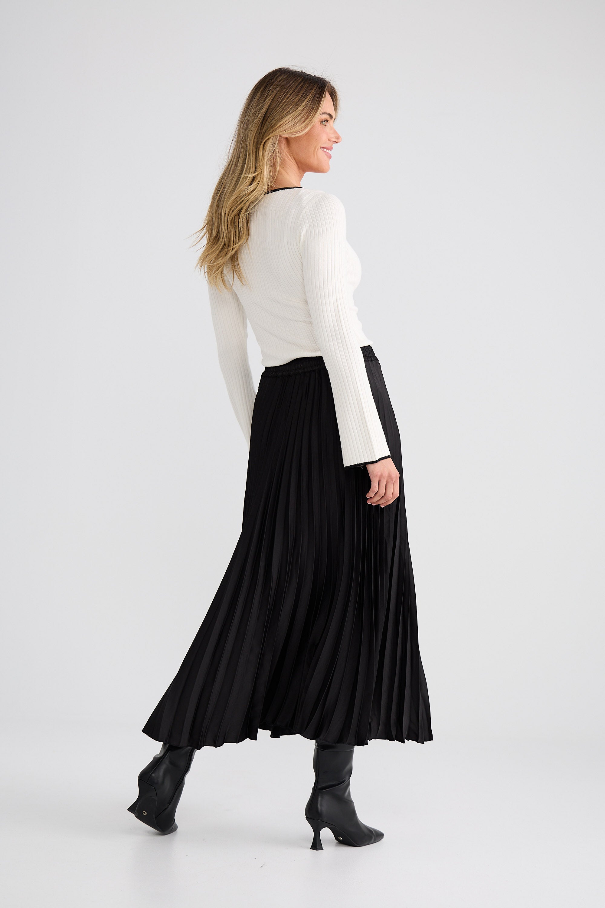 Woman wearing a white top and black pleated skirt on a white background