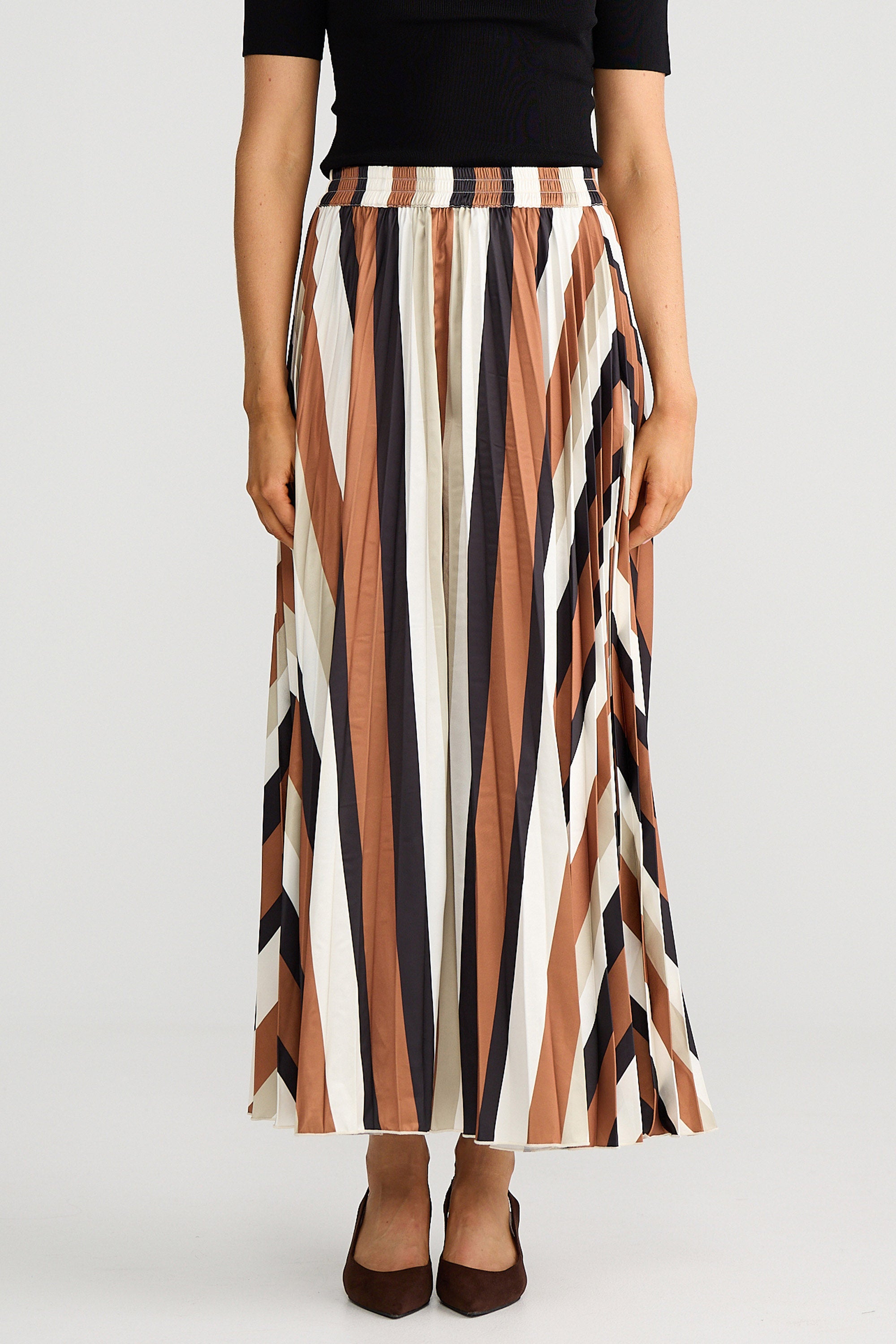 Person wearing a long, striped skirt with vertical brown, white, and black stripes on a plain background.