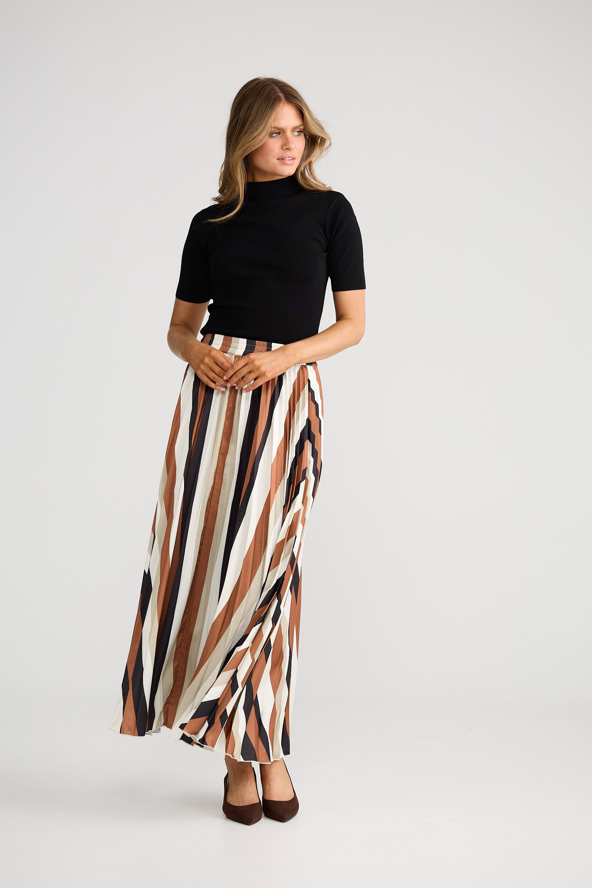 Woman wearing a black top and striped skirt on a white background