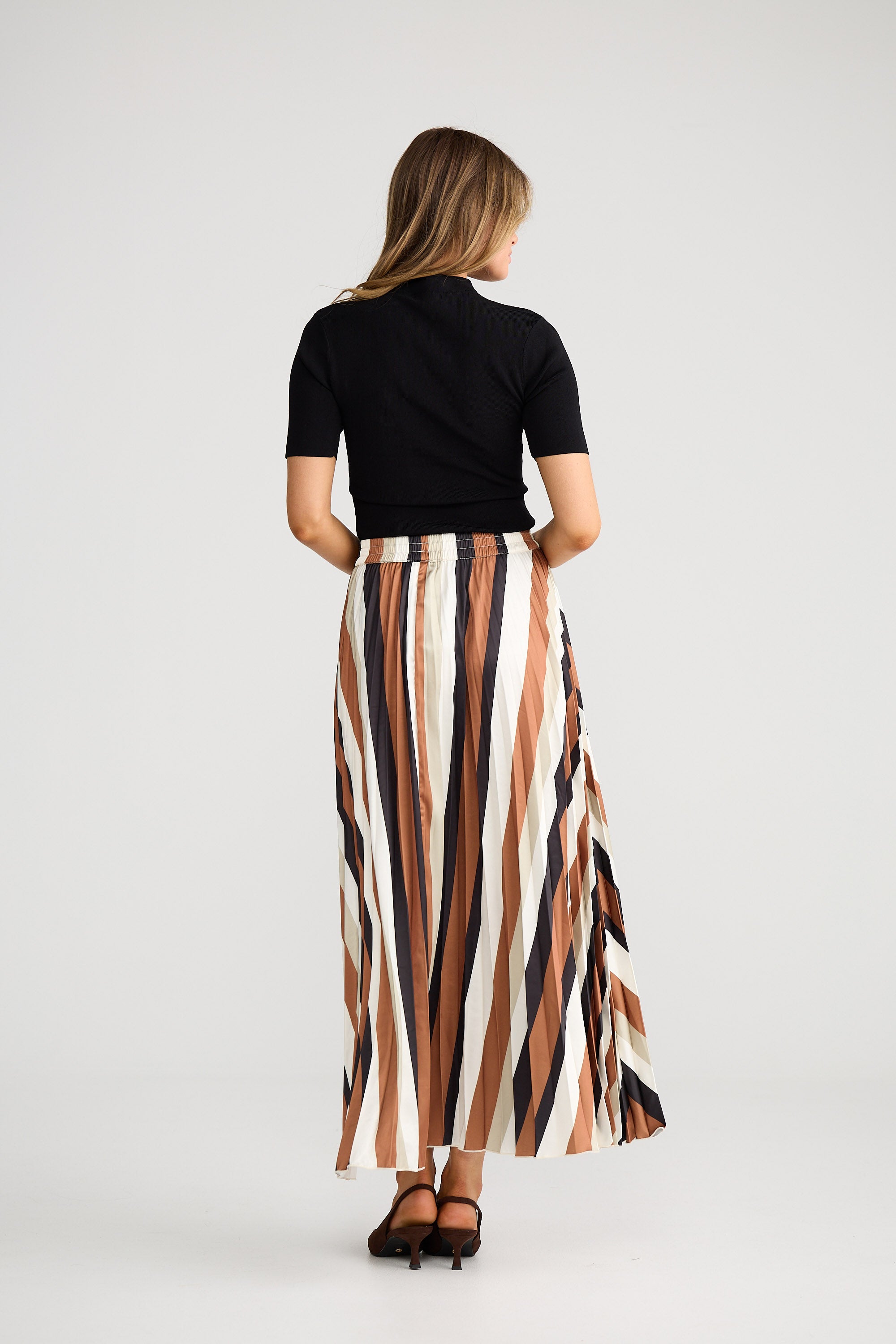 Woman wearing a black top and striped skirt on a white background
