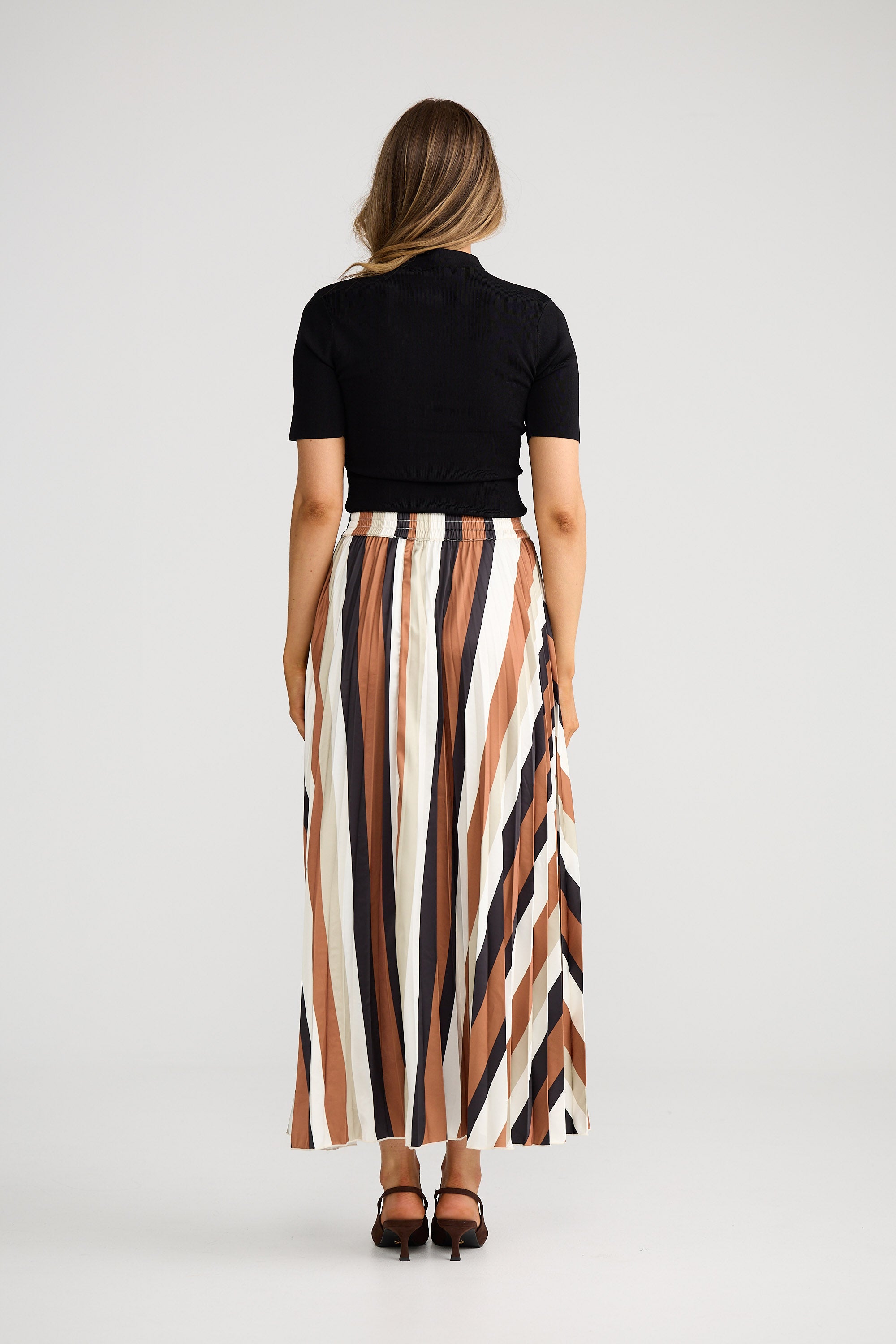 Woman wearing a black top and striped skirt on a white background