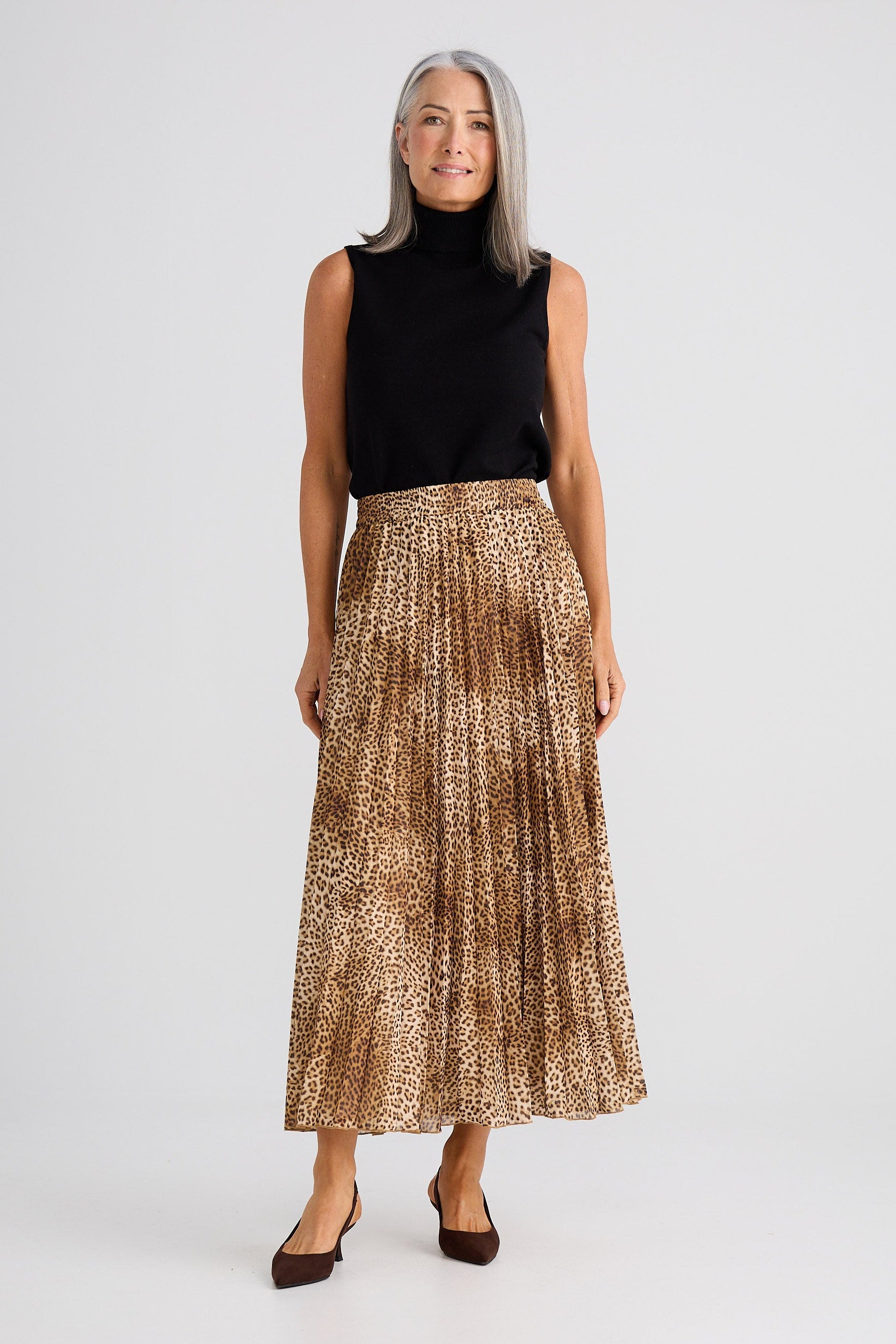 Woman wearing a black top and gold pleated skirt on a white background