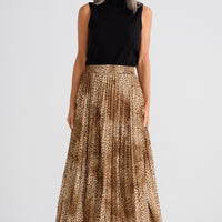 Woman wearing a black sleeveless top and gold patterned skirt on a white background