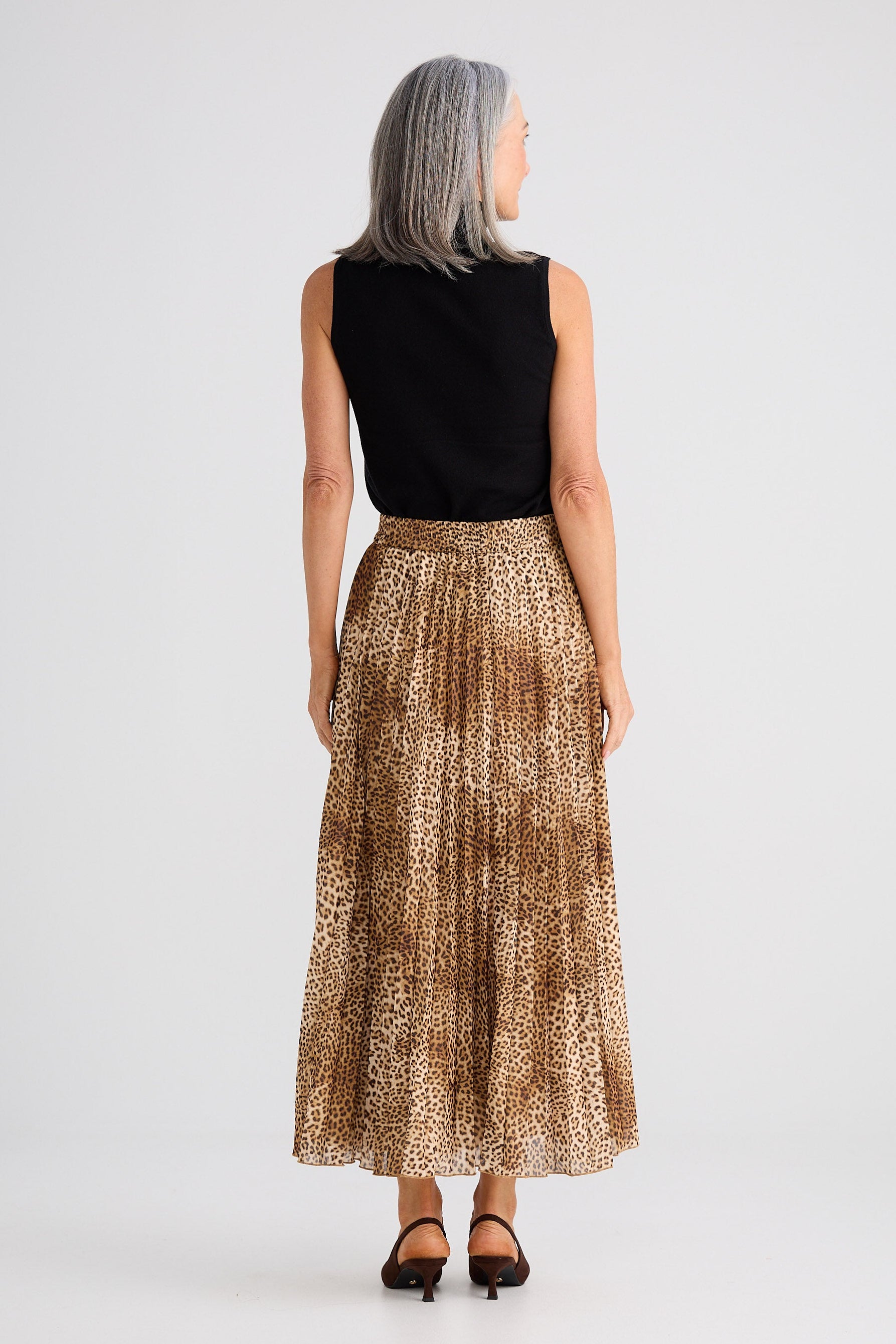 Woman wearing a black top and patterned skirt on a white background