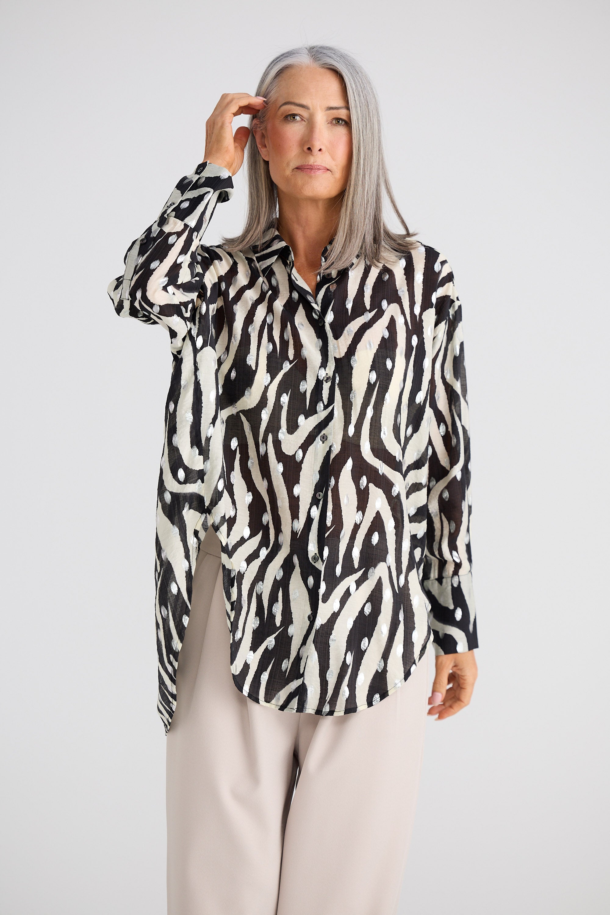 Woman wearing a black and white patterned blouse against a plain background