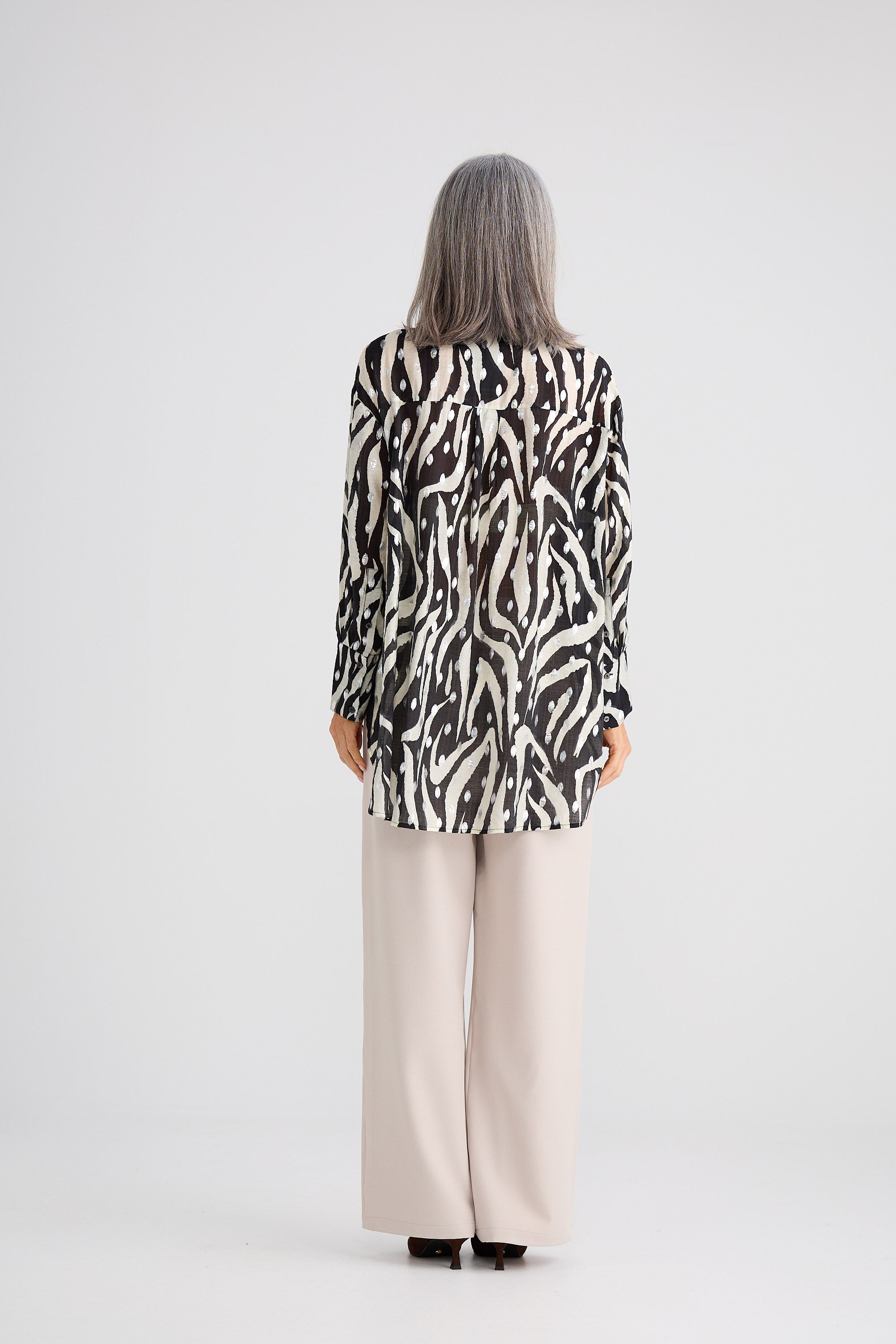 Person wearing a zebra print top and beige pants on a white background