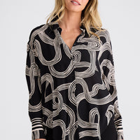 Woman wearing a black and white patterned blouse against a plain background