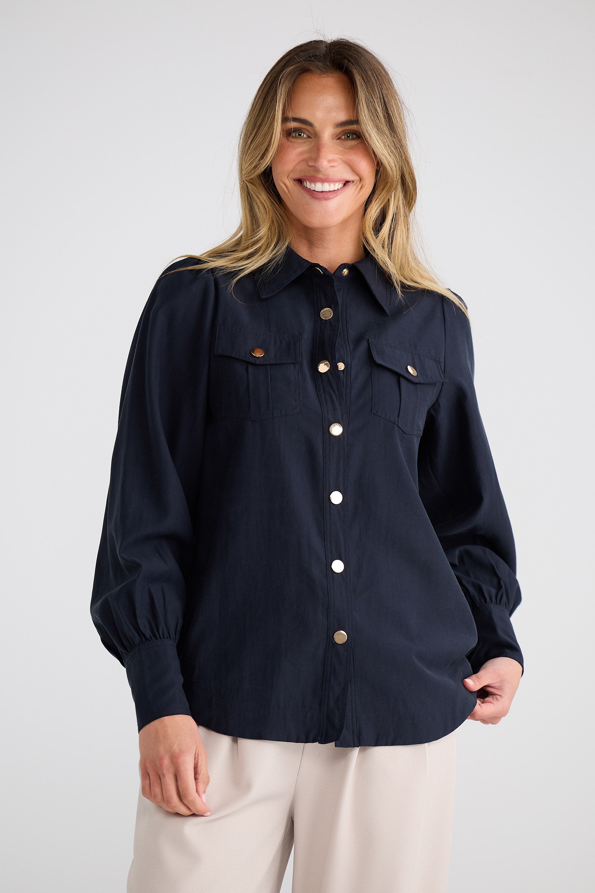 Woman wearing a navy blue shirt with buttons on a white background