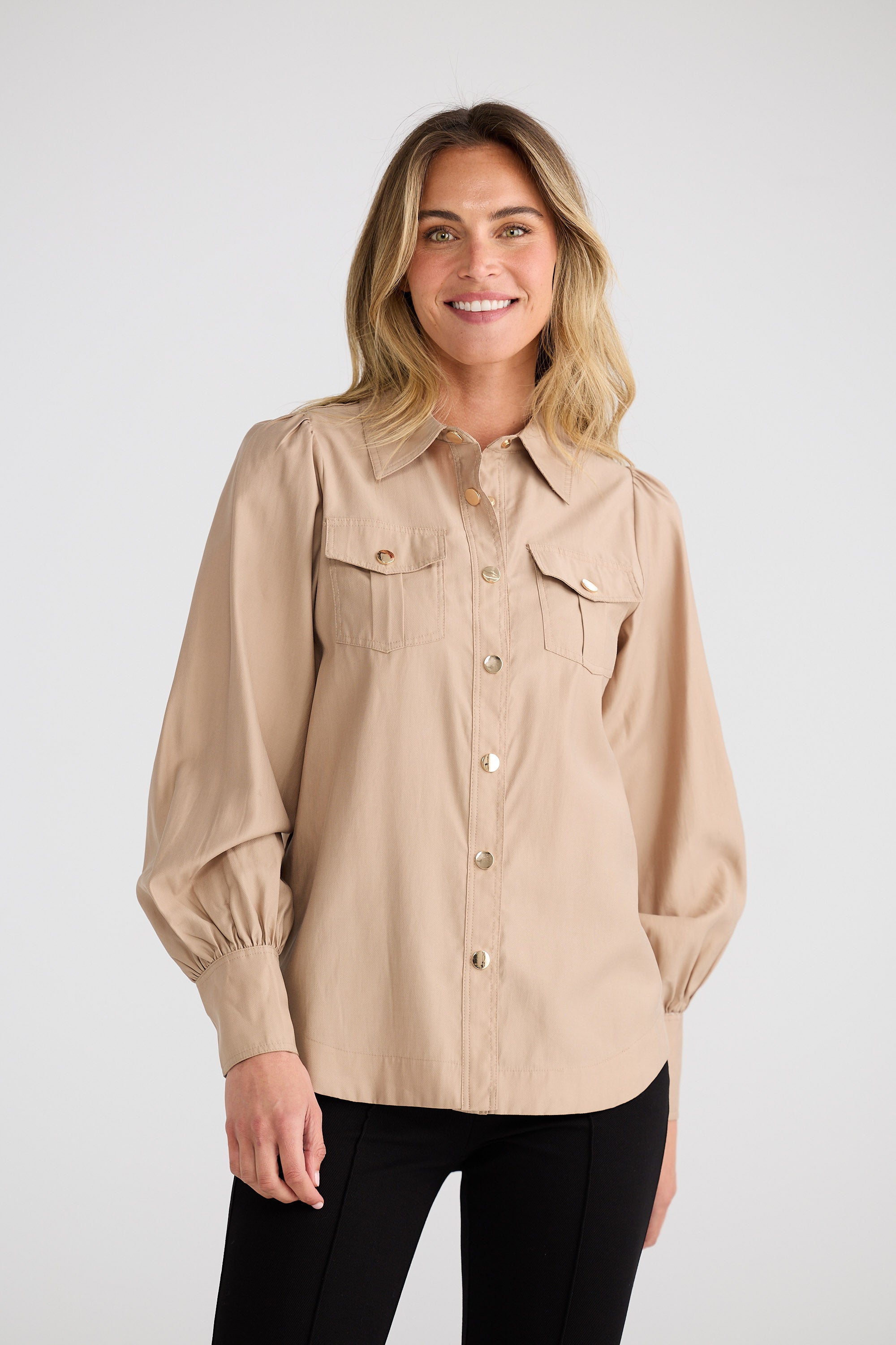 Woman wearing a beige shirt with a plain background