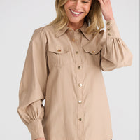 Woman wearing a beige blouse with black pants on a white background