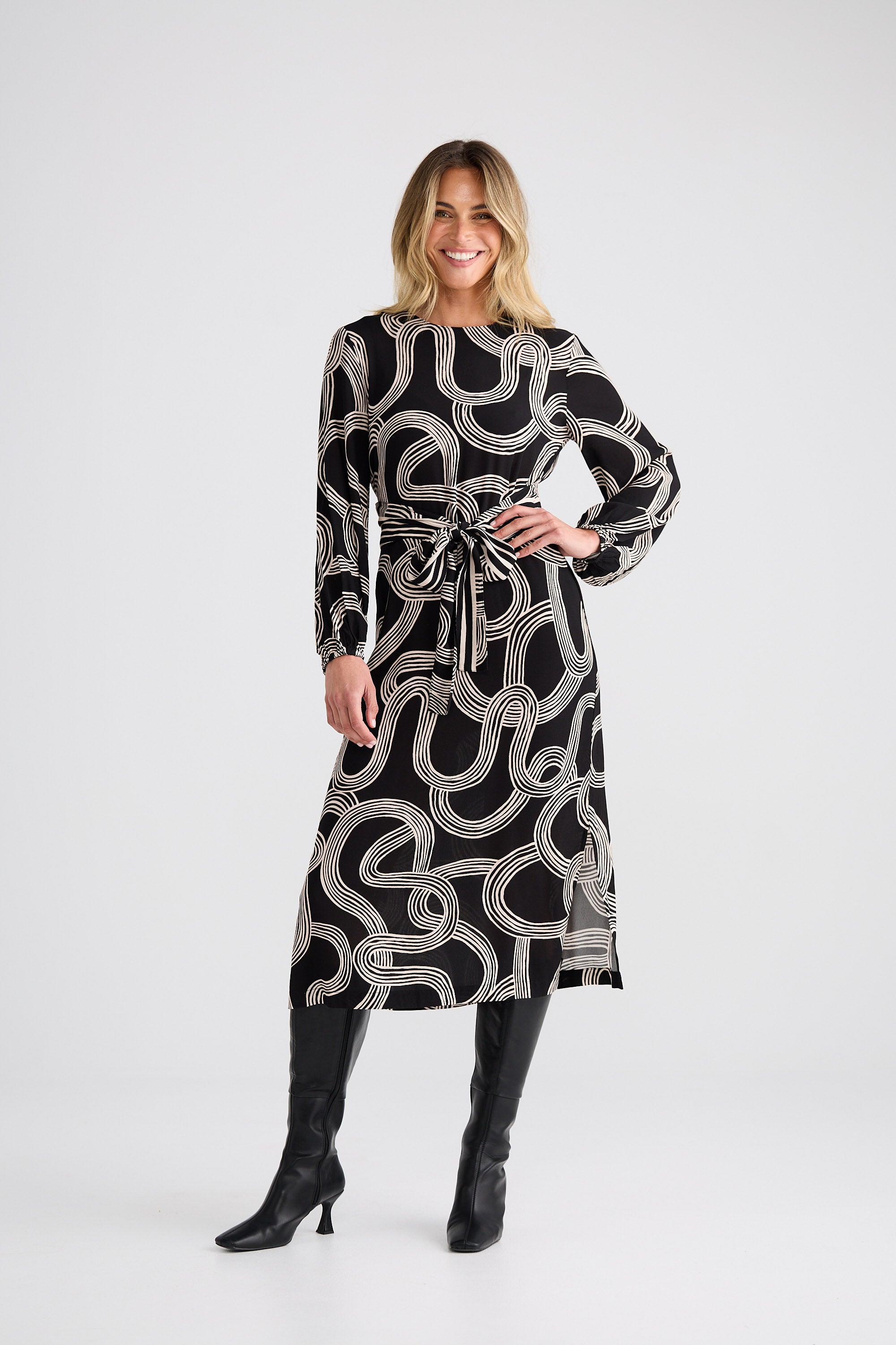 Woman wearing a black and white patterned dress with long sleeves on a white background