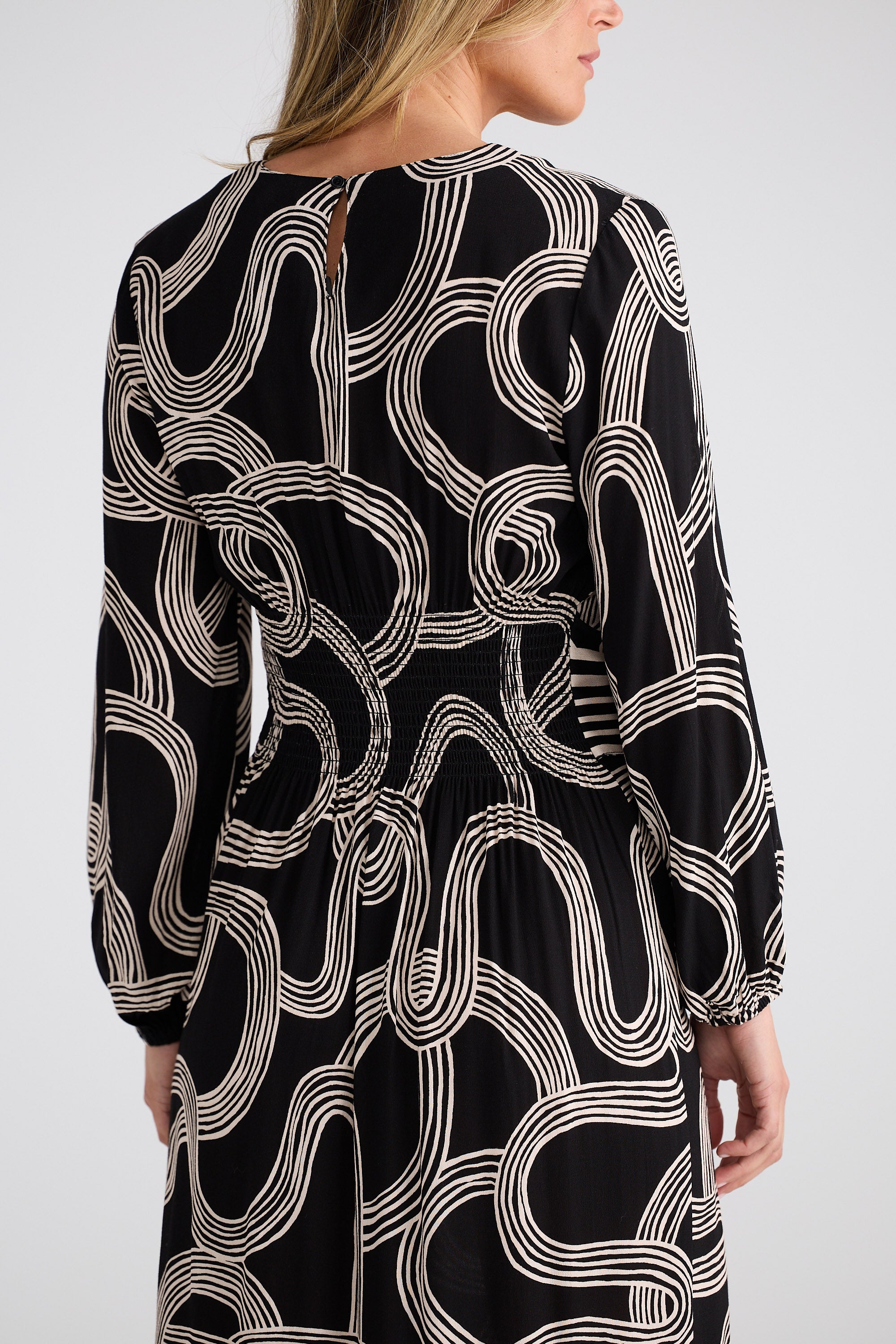 Black dress with white abstract pattern worn by a person on a light gray background