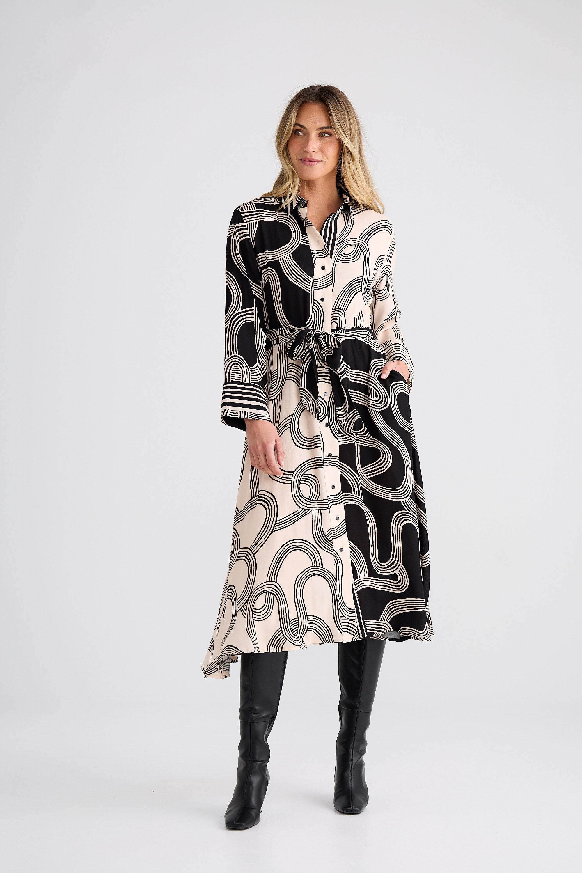 Woman wearing a long, patterned dress with a belt on a white background