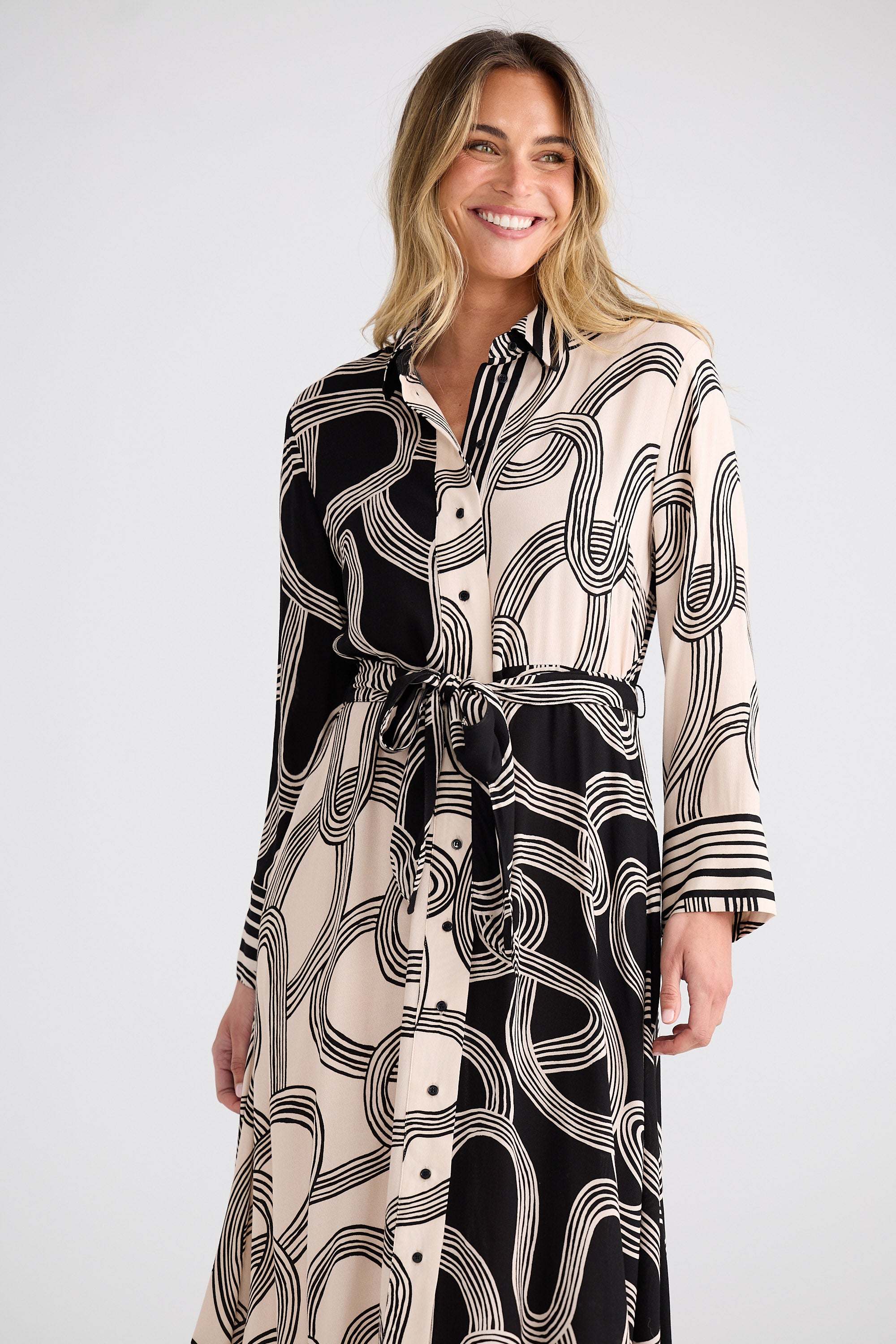 Woman wearing a black and white patterned dress on a plain background