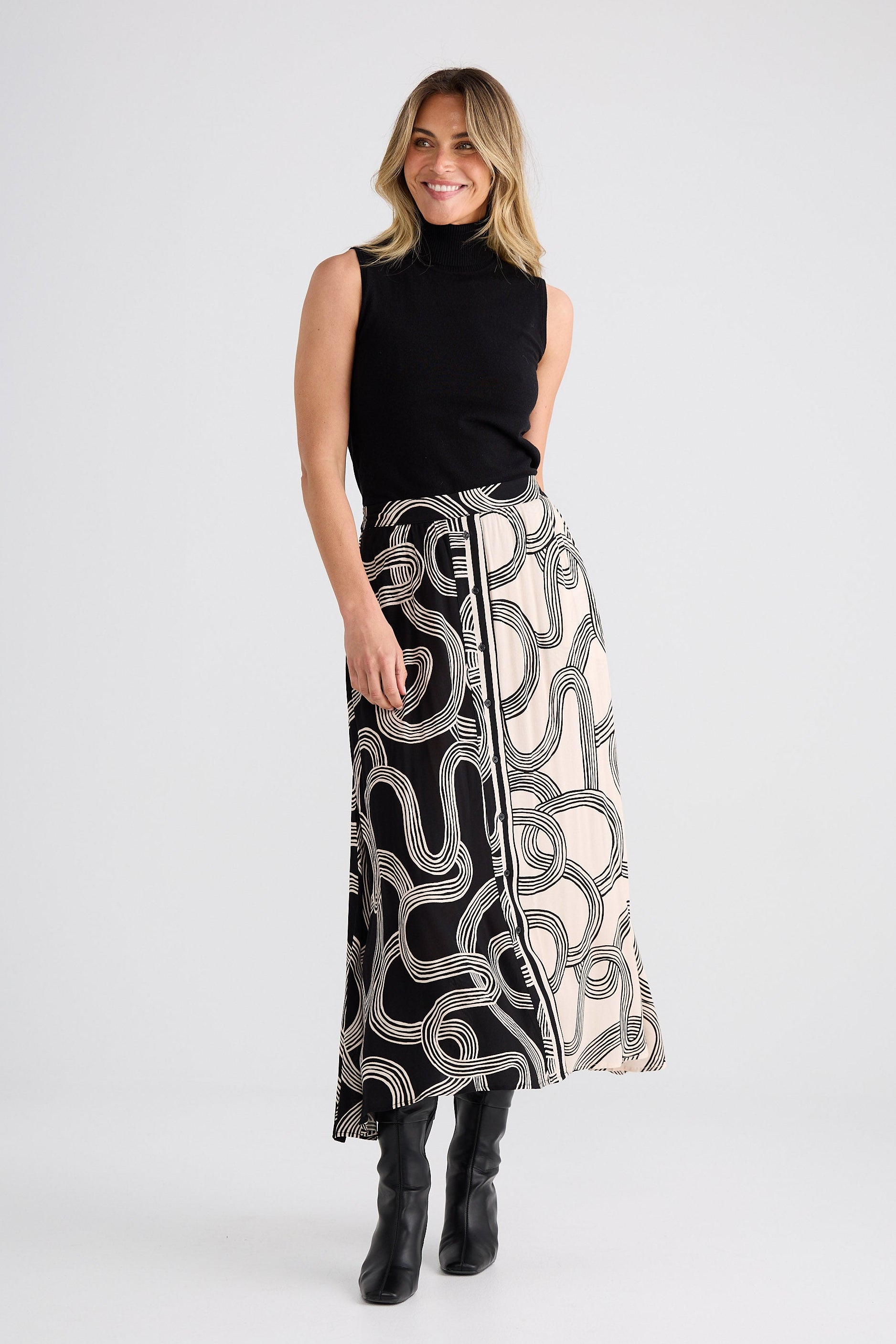 Woman wearing a black sleeveless top and patterned skirt on a white background