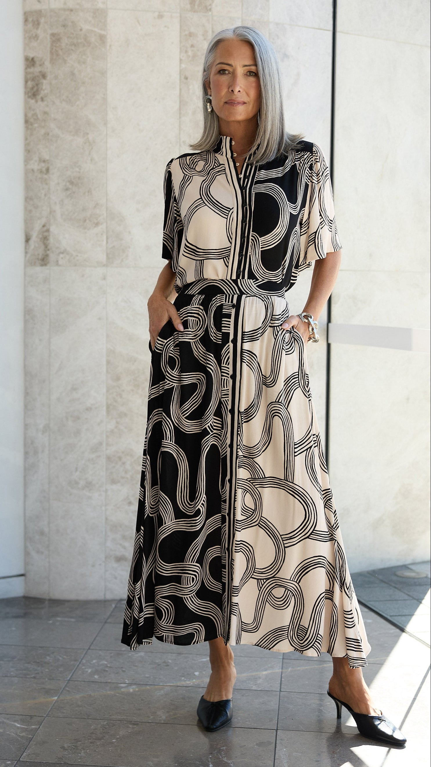 Woman wearing a black and white patterned outfit in a modern indoor setting