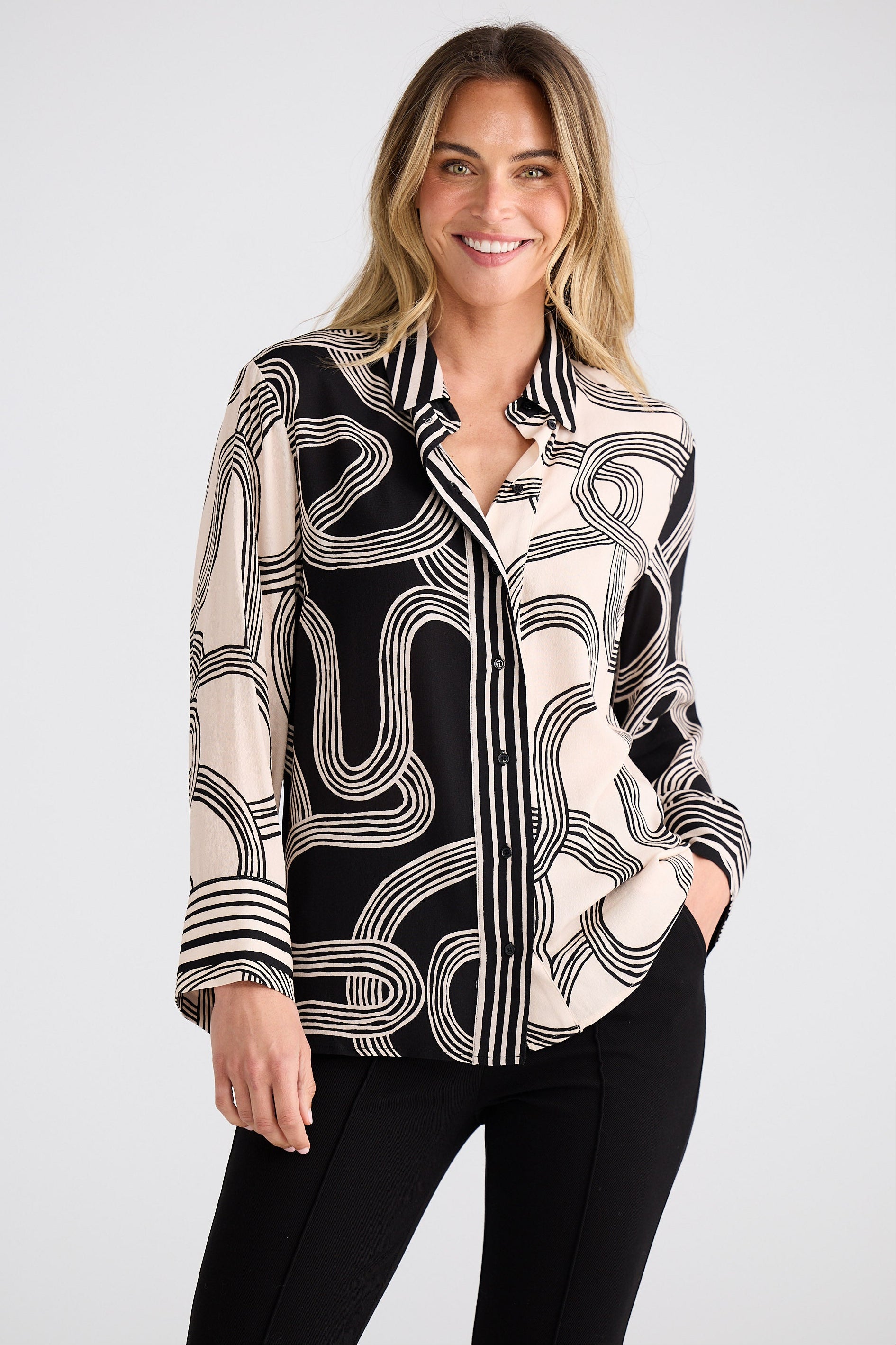 Woman wearing a black and white patterned blouse against a plain background