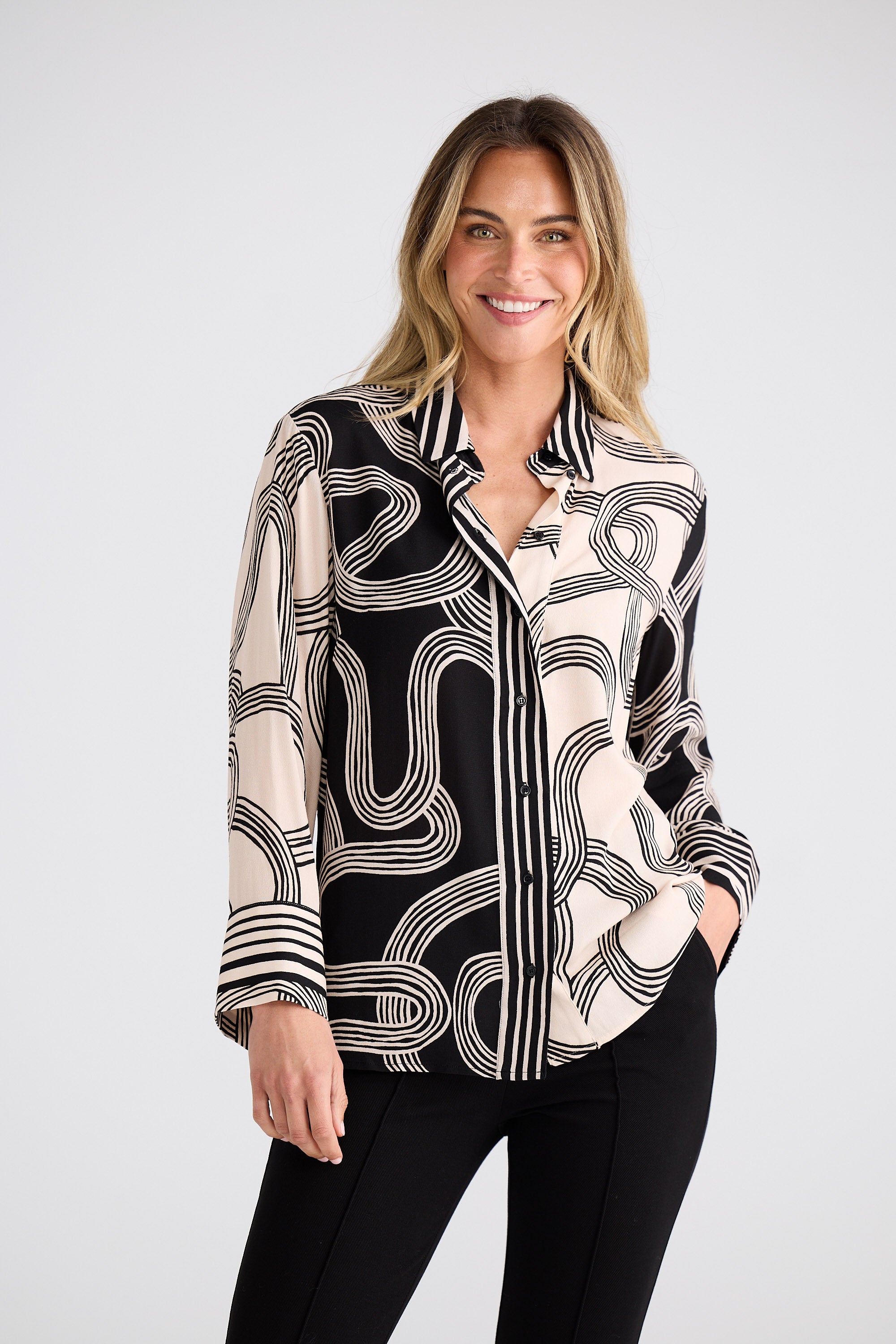 Woman wearing a black and white patterned blouse against a plain background