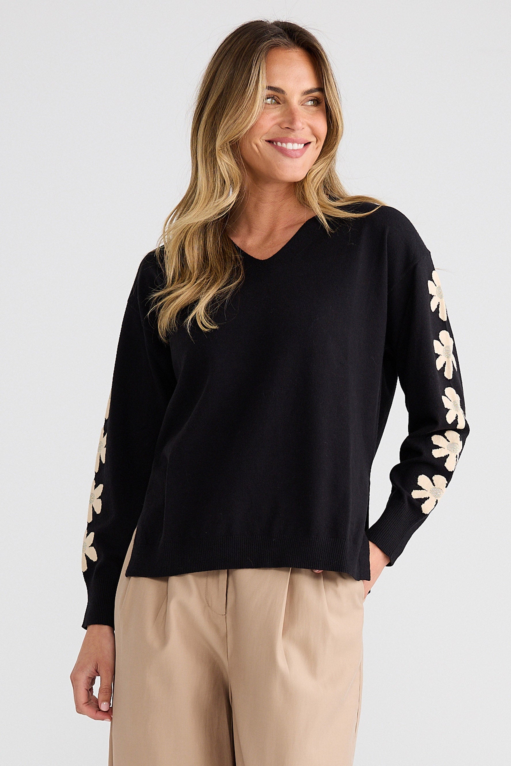 Woman wearing a black long-sleeve top with floral patterns on a white background