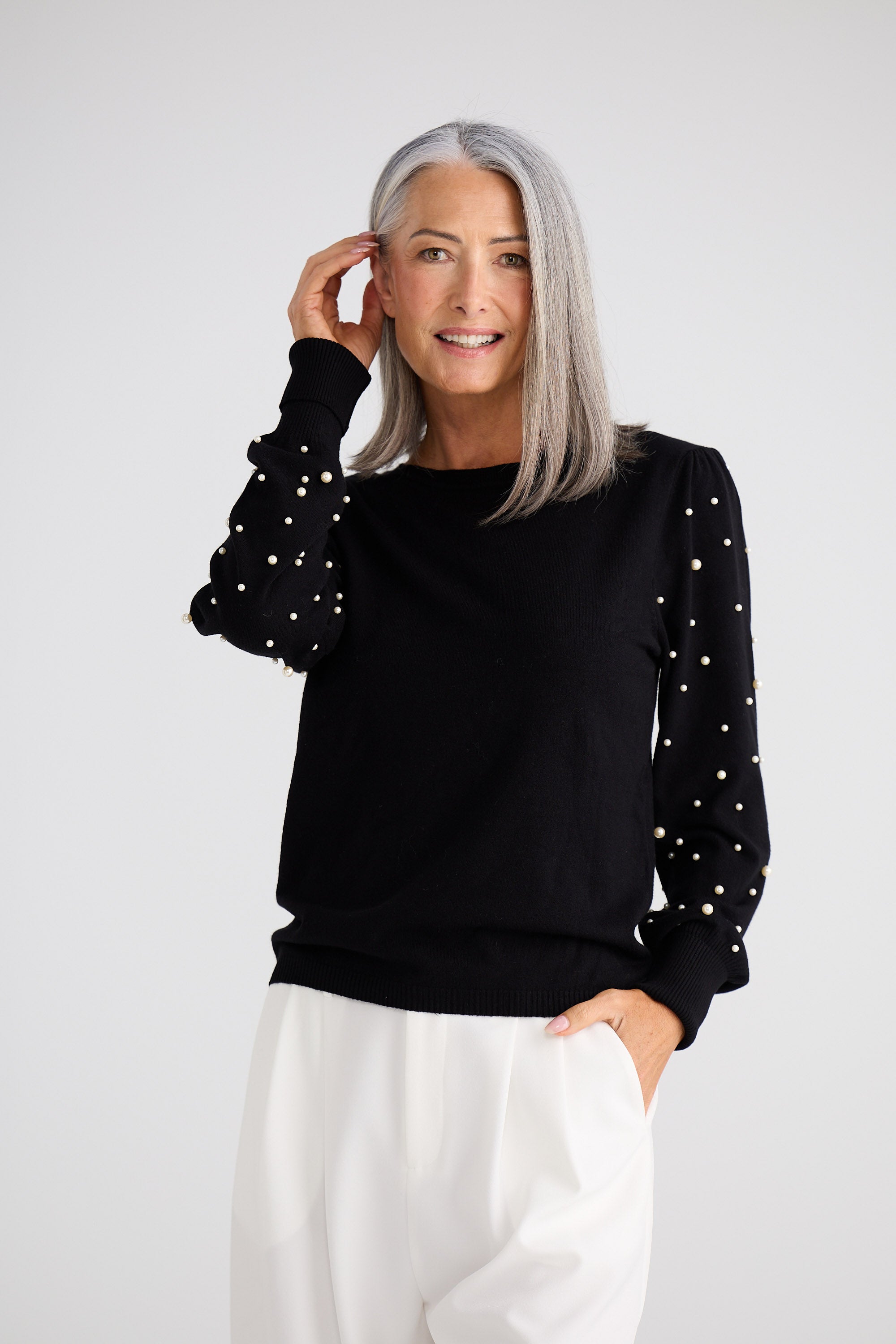Woman wearing a black sweater with white polka dots on a white background