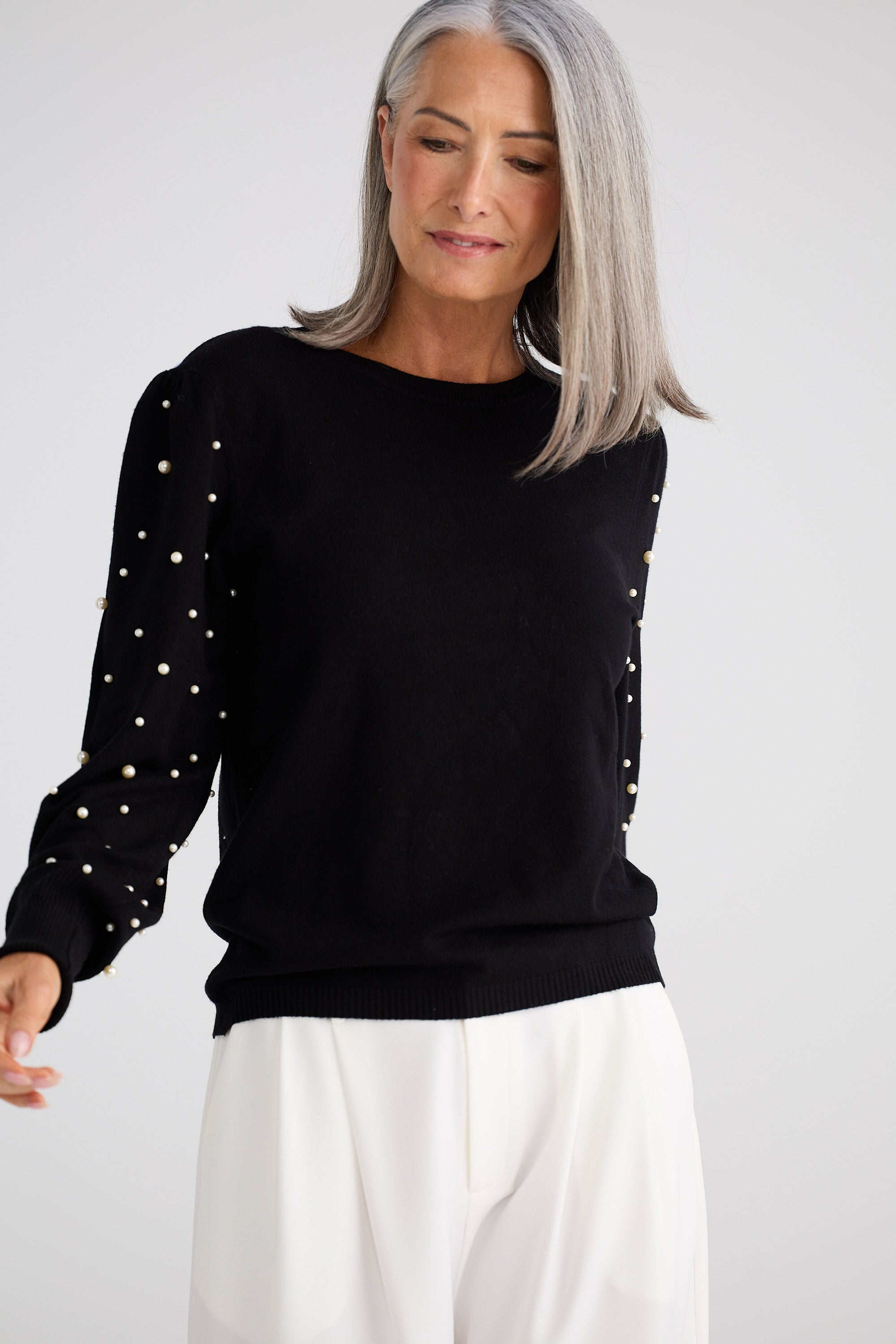 Woman wearing a black sweater with white polka dots on sleeves against a white background