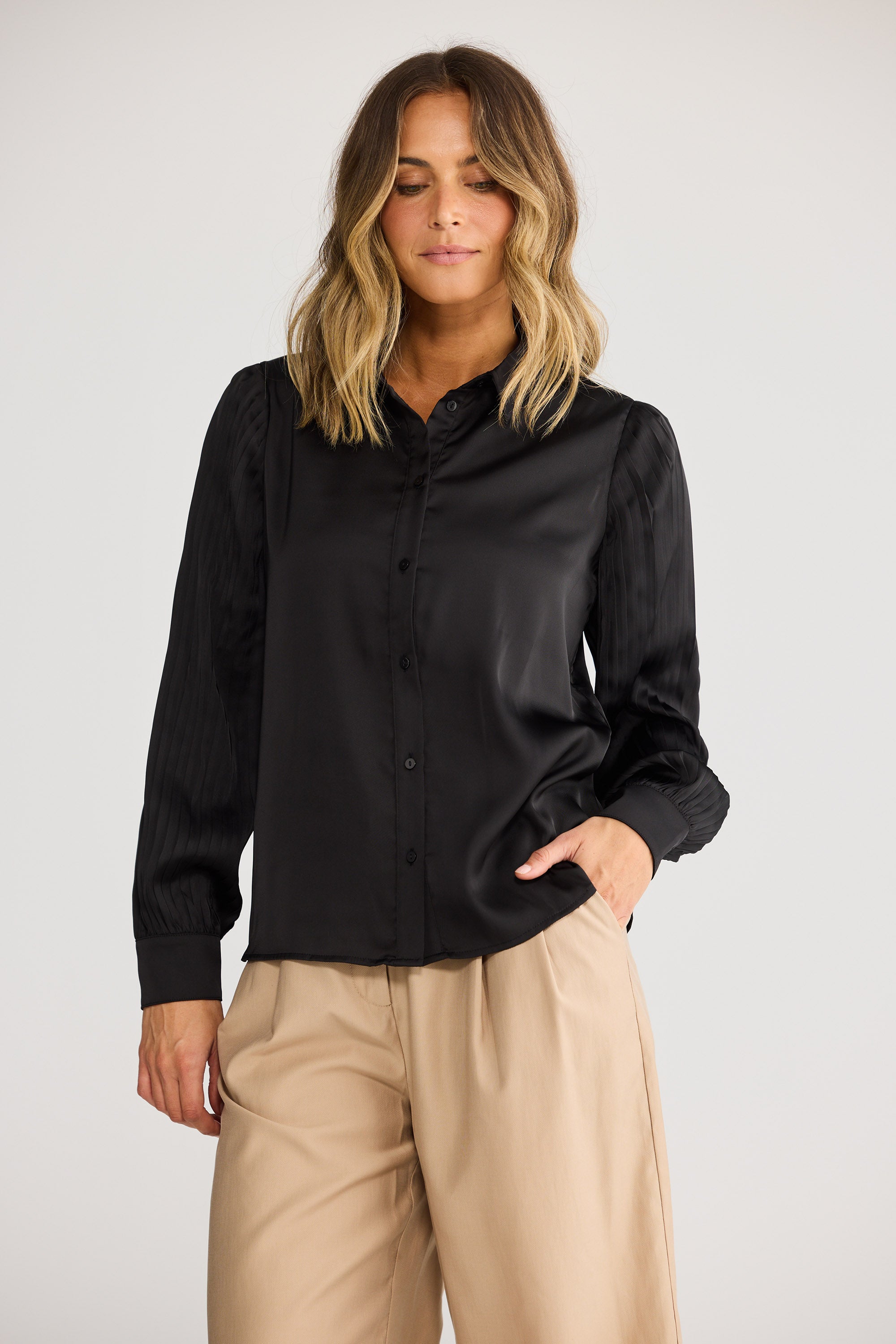 Woman wearing a black shirt and beige pants on a white background